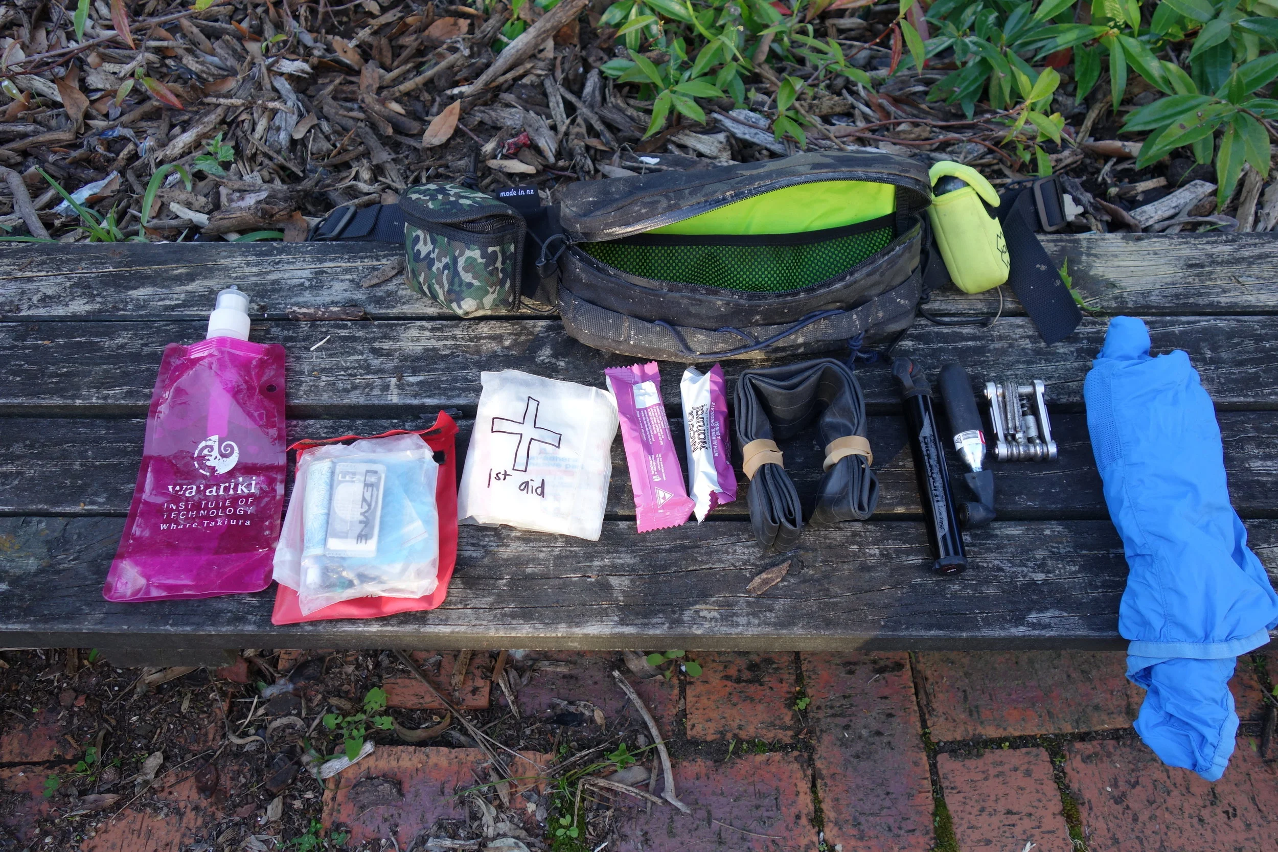 When I need to step it up a notch I go to DEFCON 2. Yes I have another completely separate kit. All the same stuff from DEFCON 1 but I add a pump, tube, 1st aid, collapsible bottle, a few cable ties and tape, PLB and camera (pouches attached to my Hipster Pack) and a light shell jacket or merino T. You can see the elastic cord tied on to the Hipster for carrying anything else, or for strapping it to my bike. I'm happy to go a full day mission with this kit. I have some pills for dodgy water in there too but I'm lucky that I don't need much water and backcountry streams have been reliable for me so far.