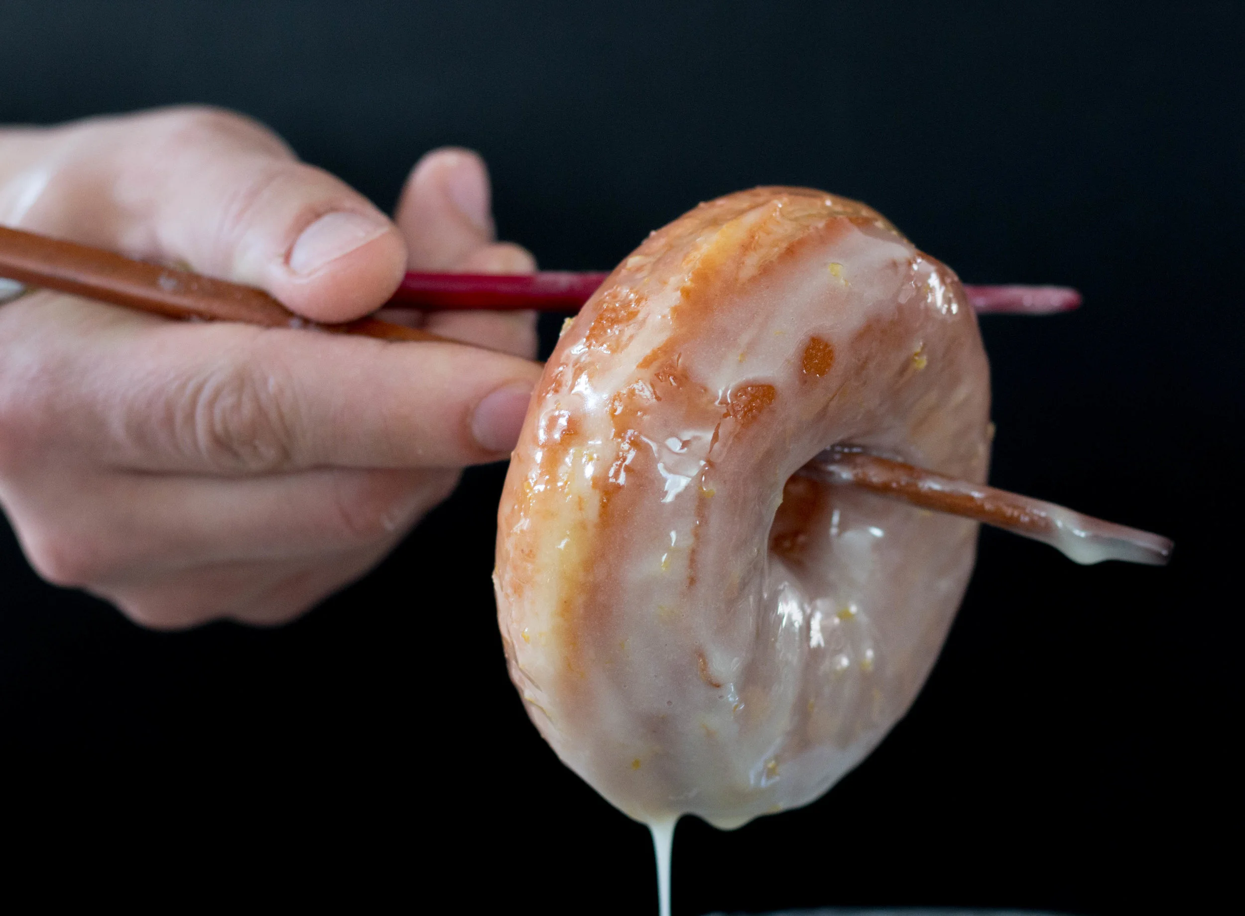 We keep the glaze room temp. Dipping the fresh fried donuts into the glaze almost "wakes" the glaze back up so that it can coat all of the fresh fried dough! Roll those suckers all around in the glaze, being sure to coat all the sides. We used chopsticks to make it easier to handle. 