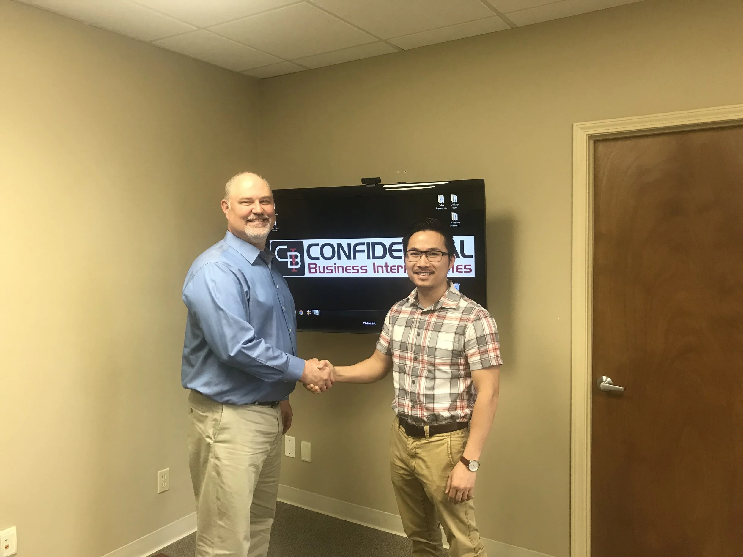 Dr. Scott Taylor (left) shakes hands with new owner, Dr. Isaac Le.