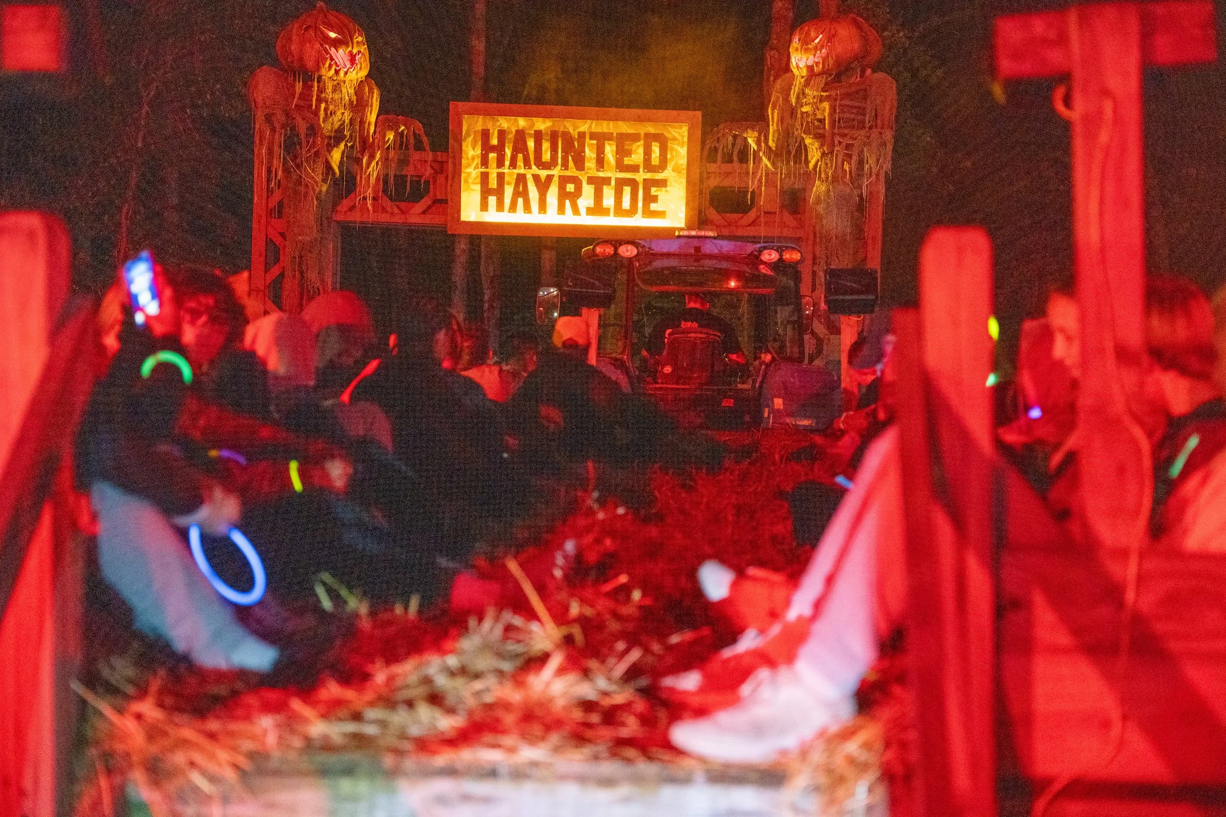 Customers on a hay wagon approaching the Haunted Hayride entrance.
