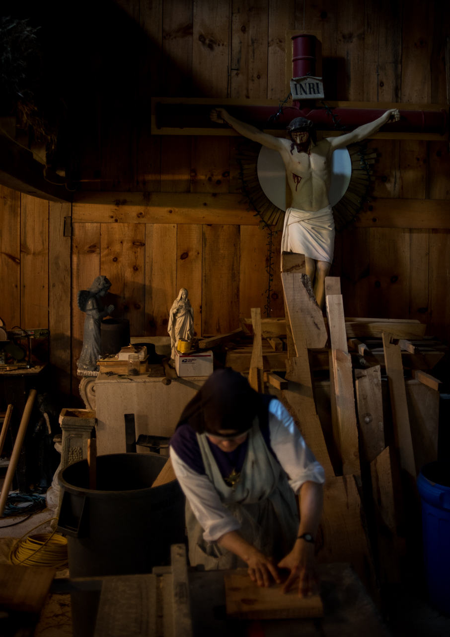 Sister Joseph Marie using a table saw to cut wood for a shelf she is making to hold food in the goat shed. 