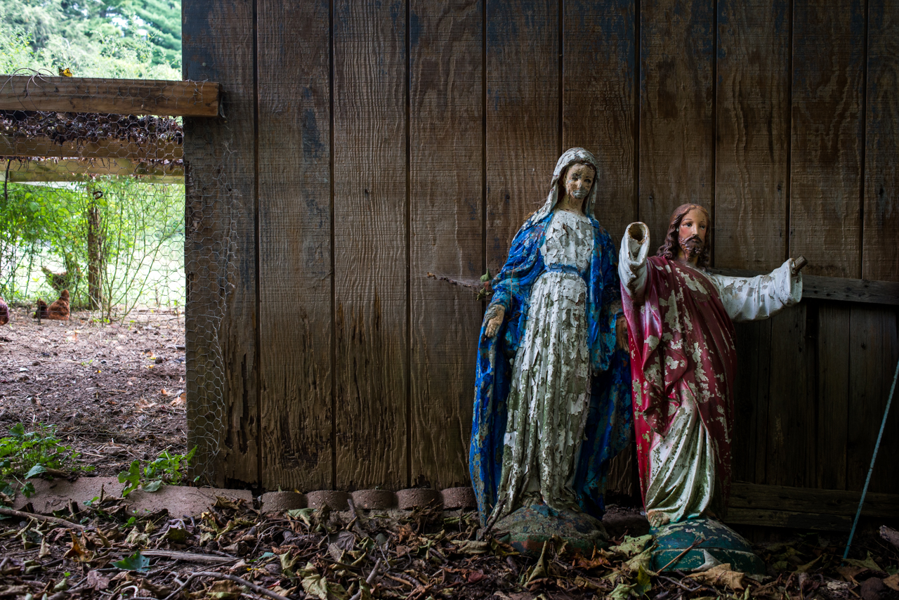 Statues of Mother Mary and Jesus, sitting behind the chicken coop after the paint began to chip and age. 