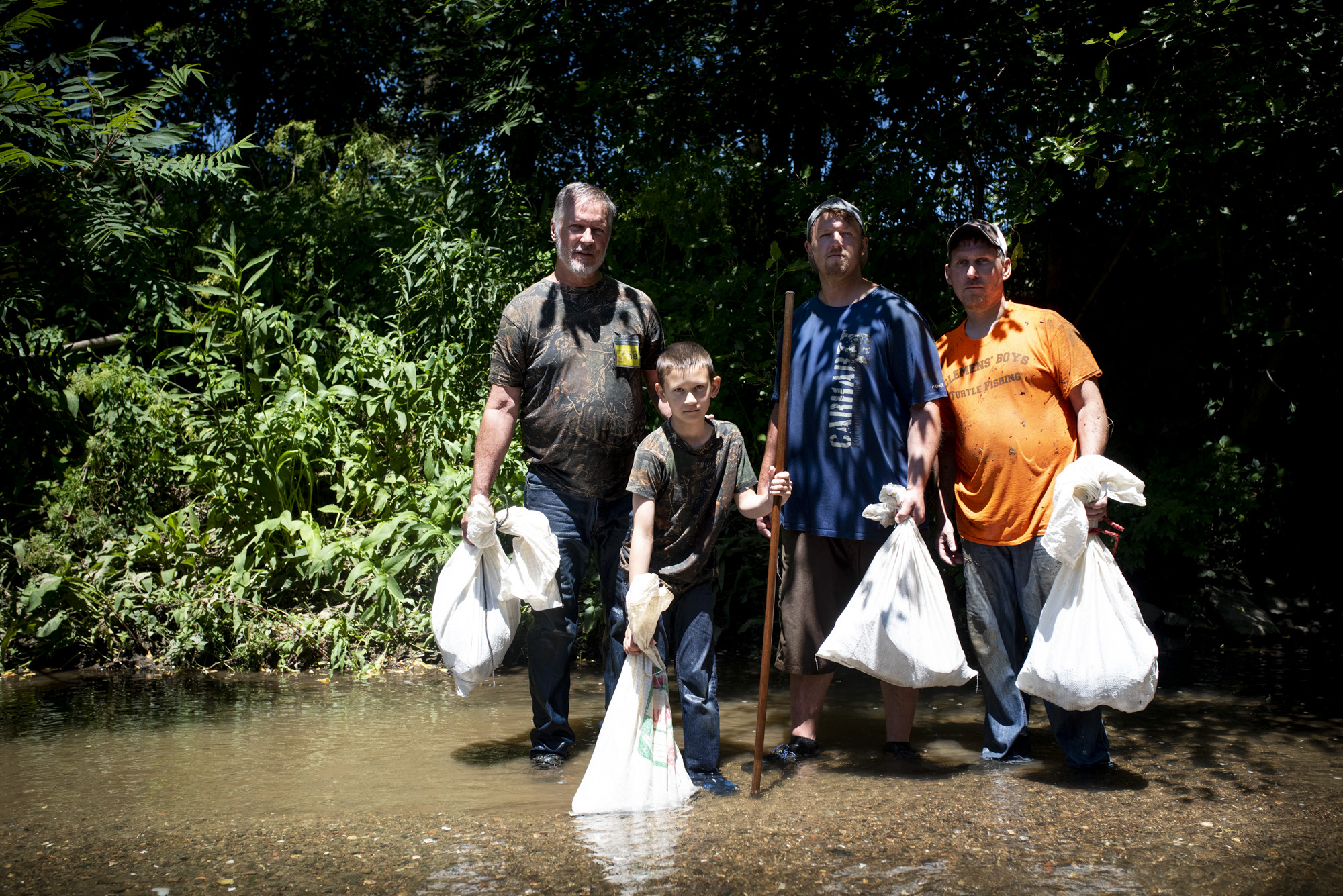 Vince, Adyn, Joey, and Joe Clemens poses for a portrait with sacks full of snapping turtles before they get out of Sewickley Creek.