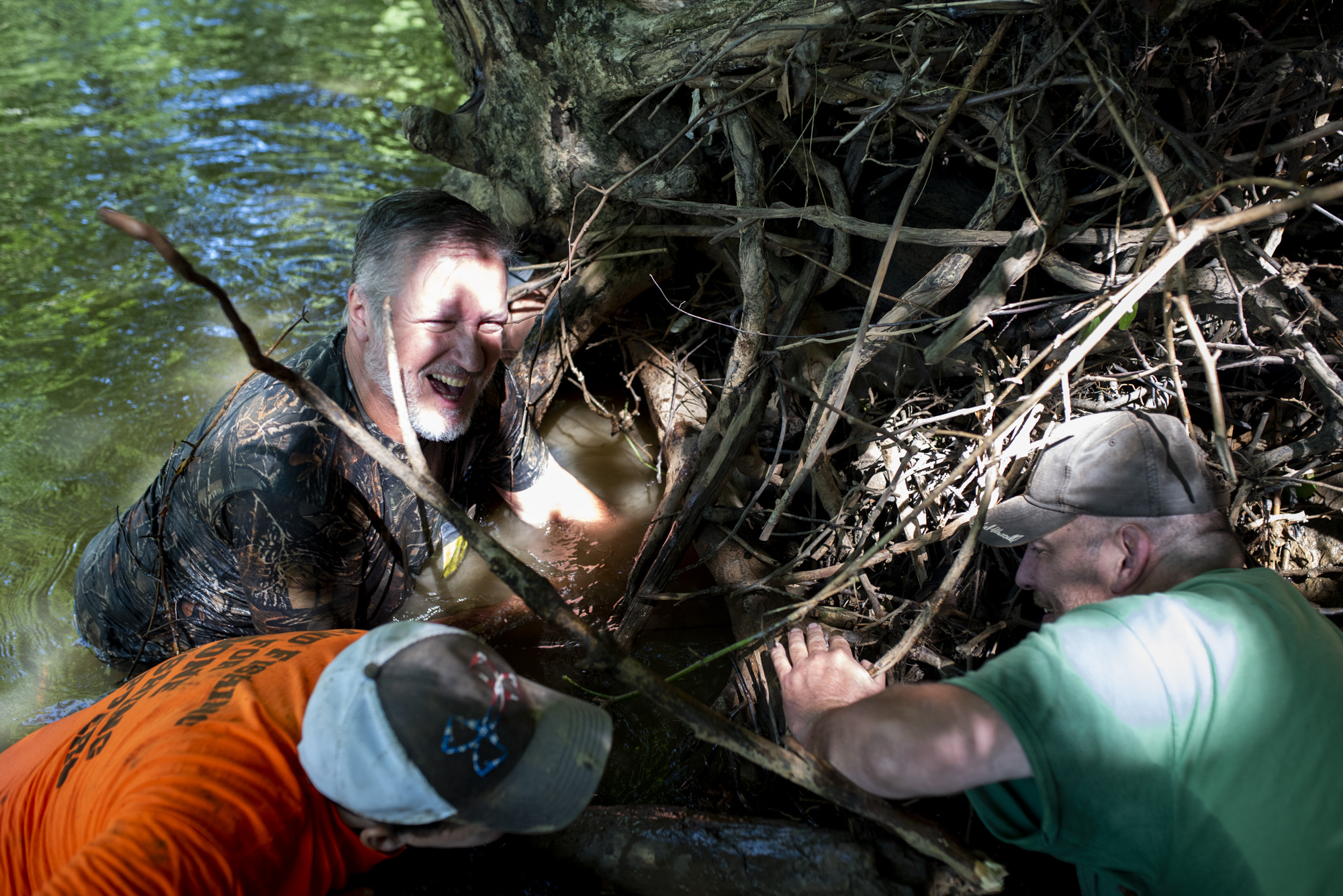 Vince, Joe, and John Clemens all reach into the the roots of a fallen tree to try to catch a snapping turtle.