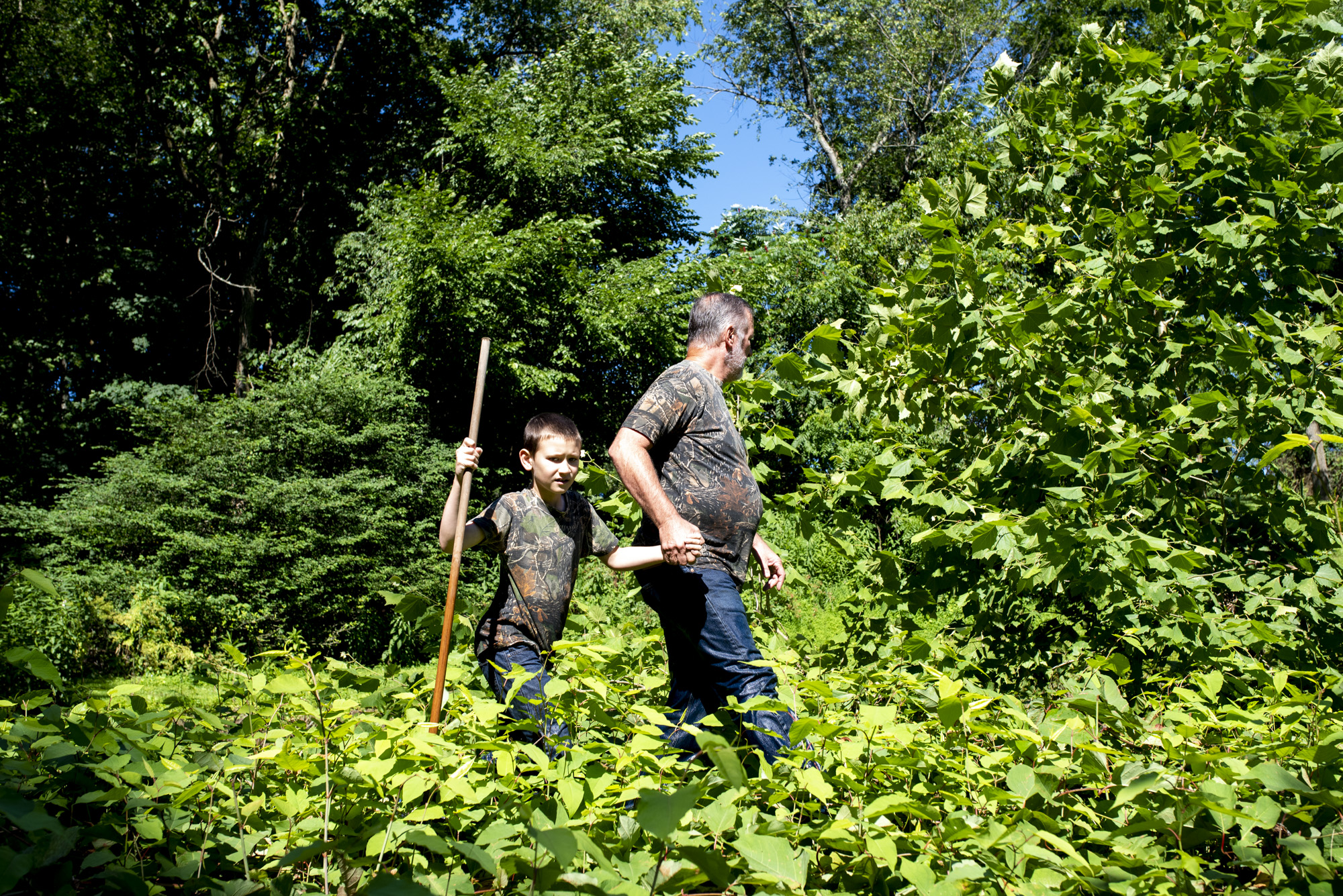 Vince Clemens and his son, Adyn Clemens, of North Huntingdon, walk through the brush to get to Brush Creek in Penn, where they hunt for snapping turtles on July 7, 2018.