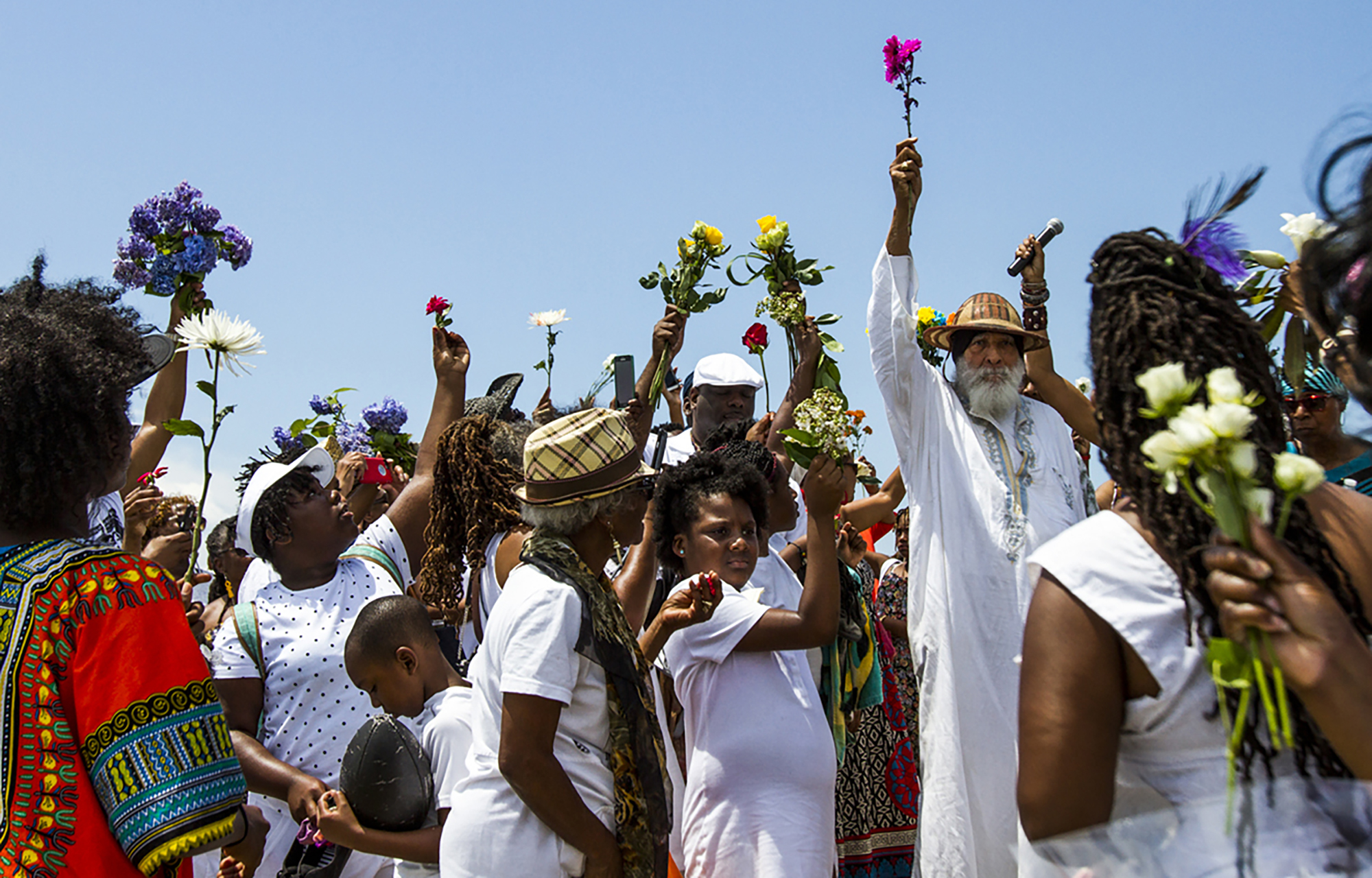  Dr. Arthur Carter holds a flower in the air during the International Day of Remembrance at Buckroe Beach on Saturday, June 10, 2017.  