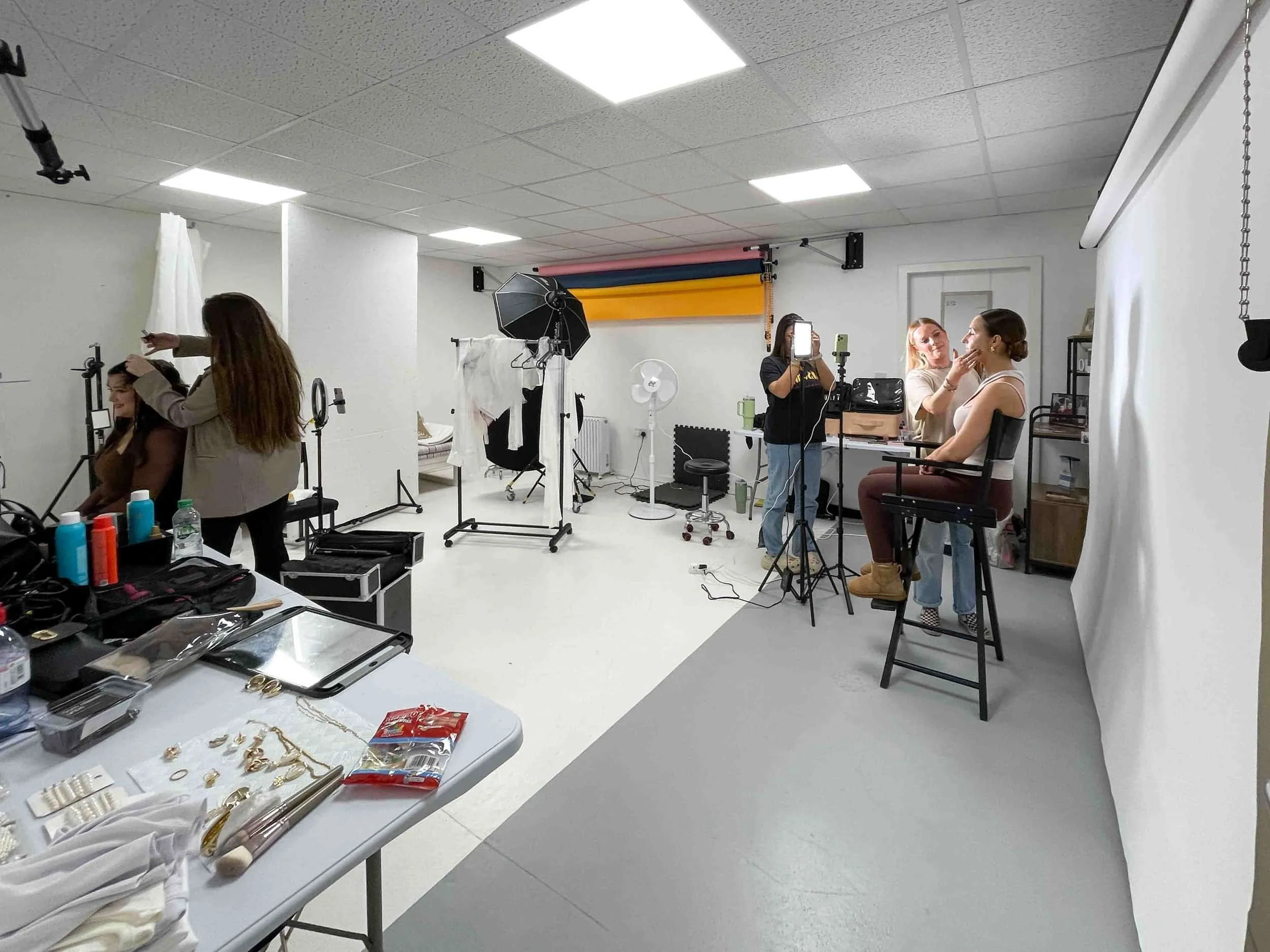 A photography studio available for studio hire, with two women getting makeup done and equipment plus supplies visible in the foreground.