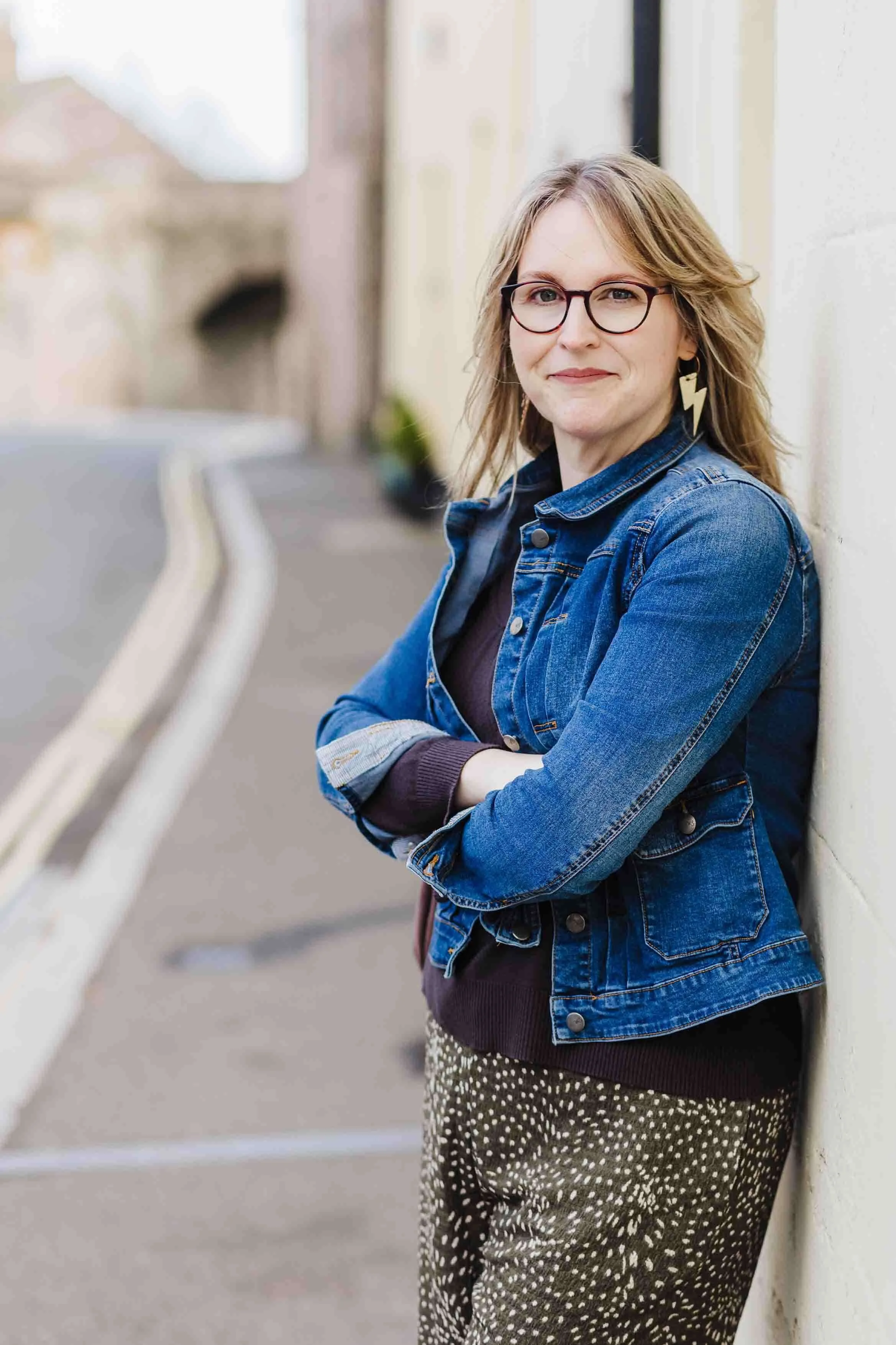 Sarah Jamieson photographer outside in Berwick's old town and smiling wearing spark gold earrings