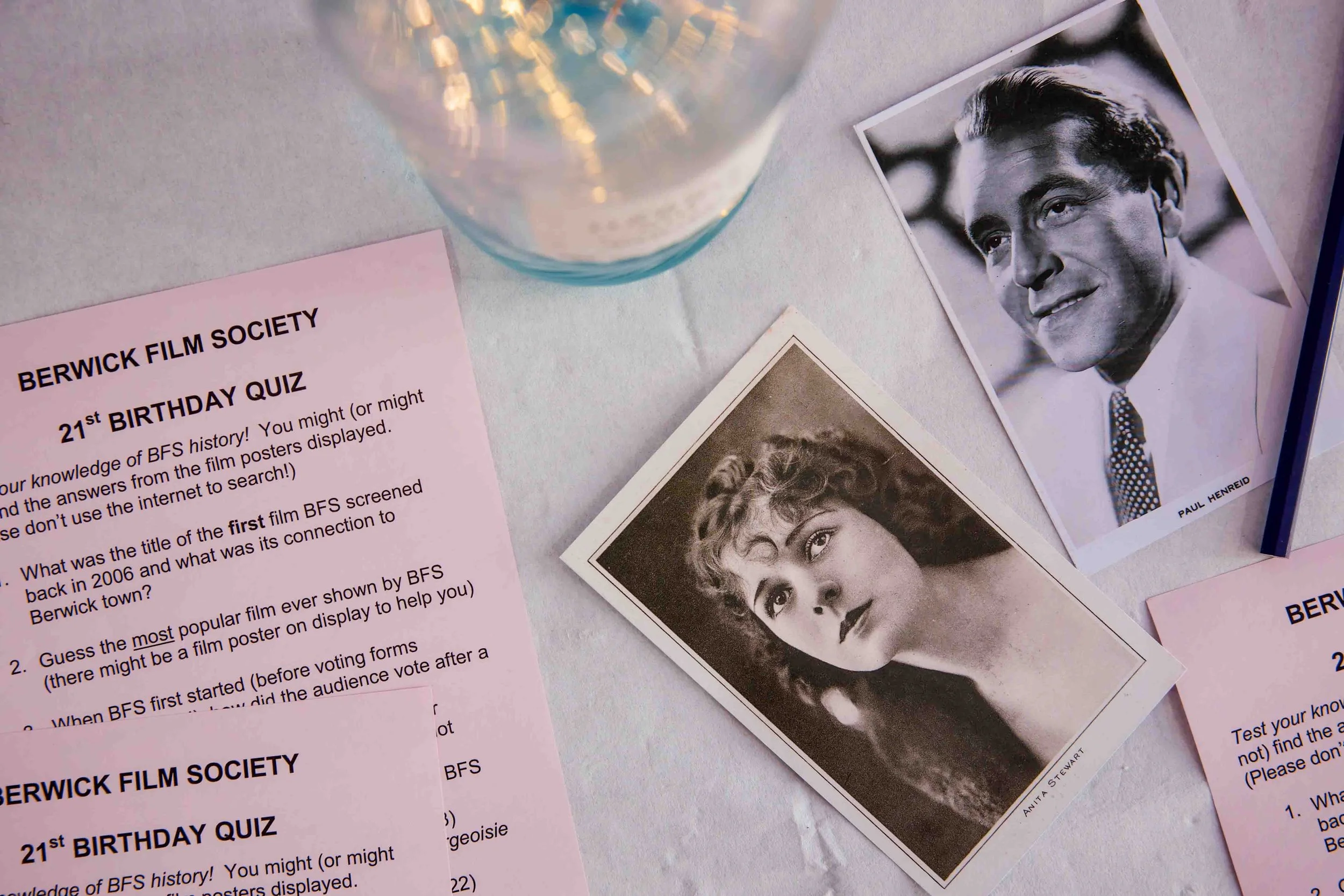 Berwick Film Society 21st birthday quiz sheets displayed on a table with vintage film star postcards.