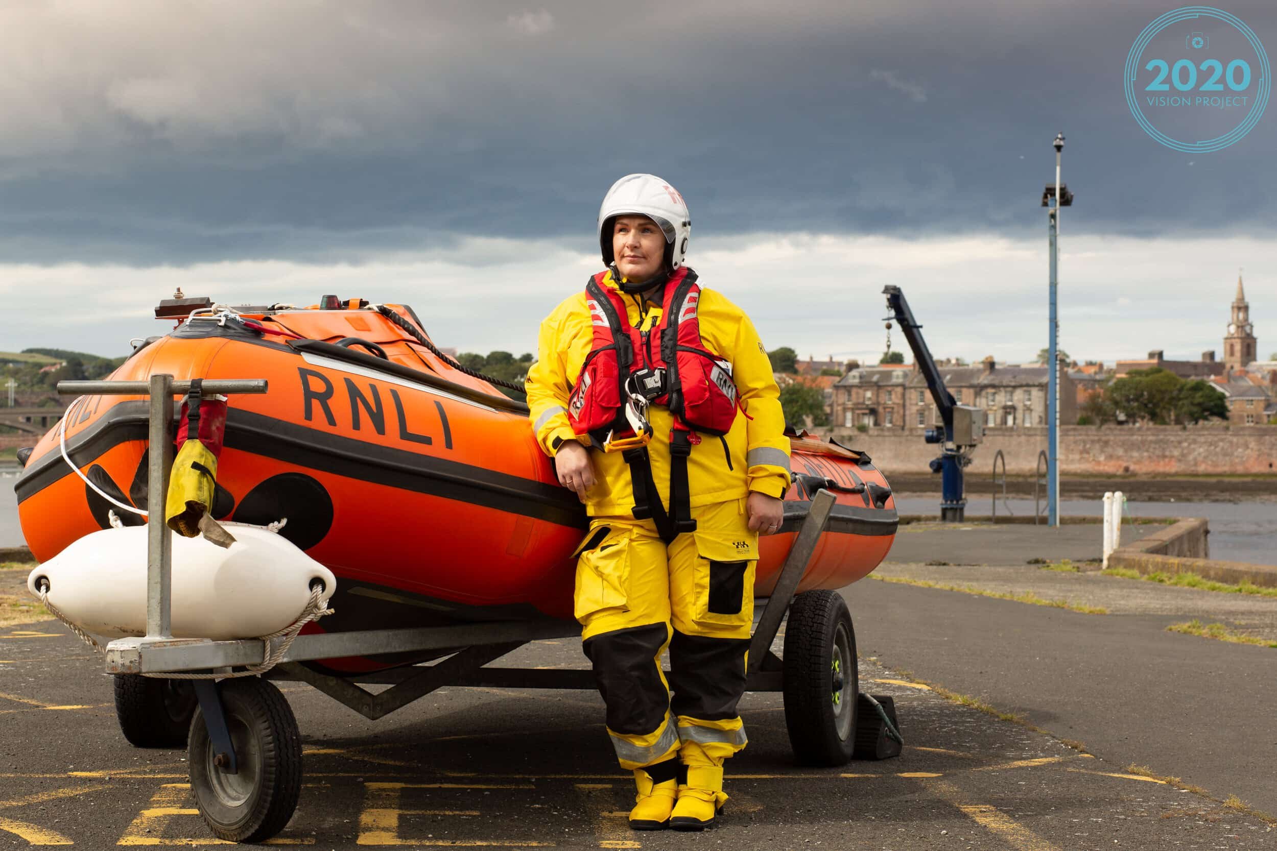 female lifeguard leaning on boat with berwick skyline in the backgound