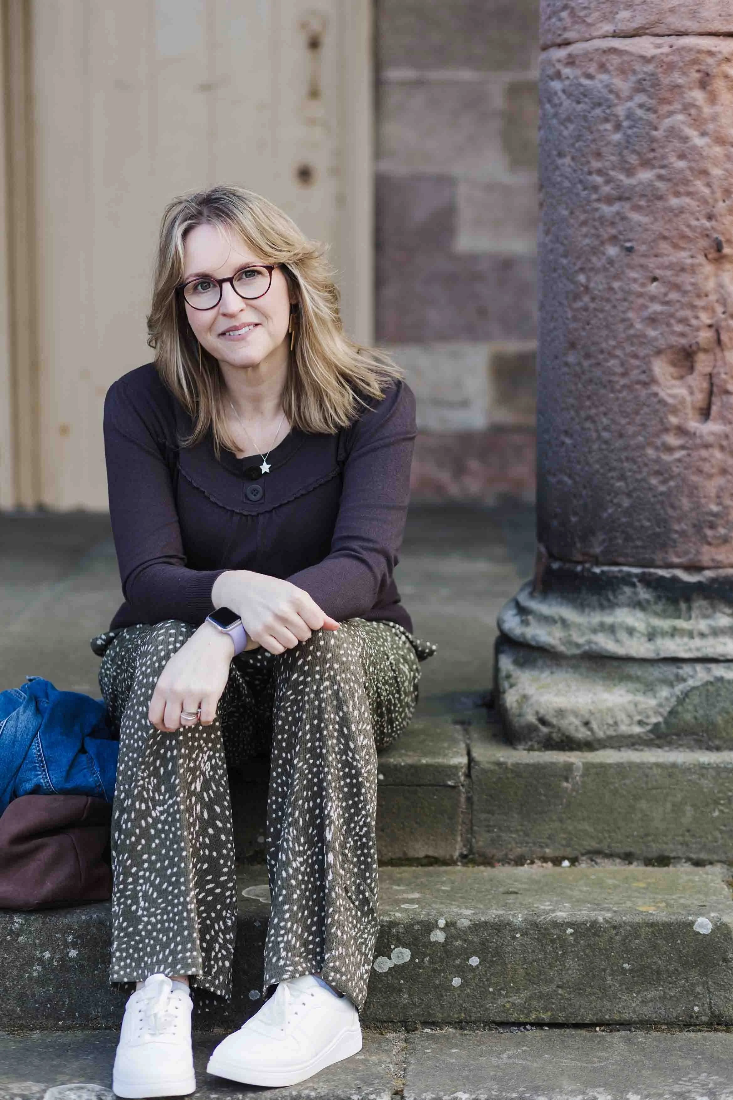 photogapher sarah on location in berwick sitting beside an old worn sandstone column