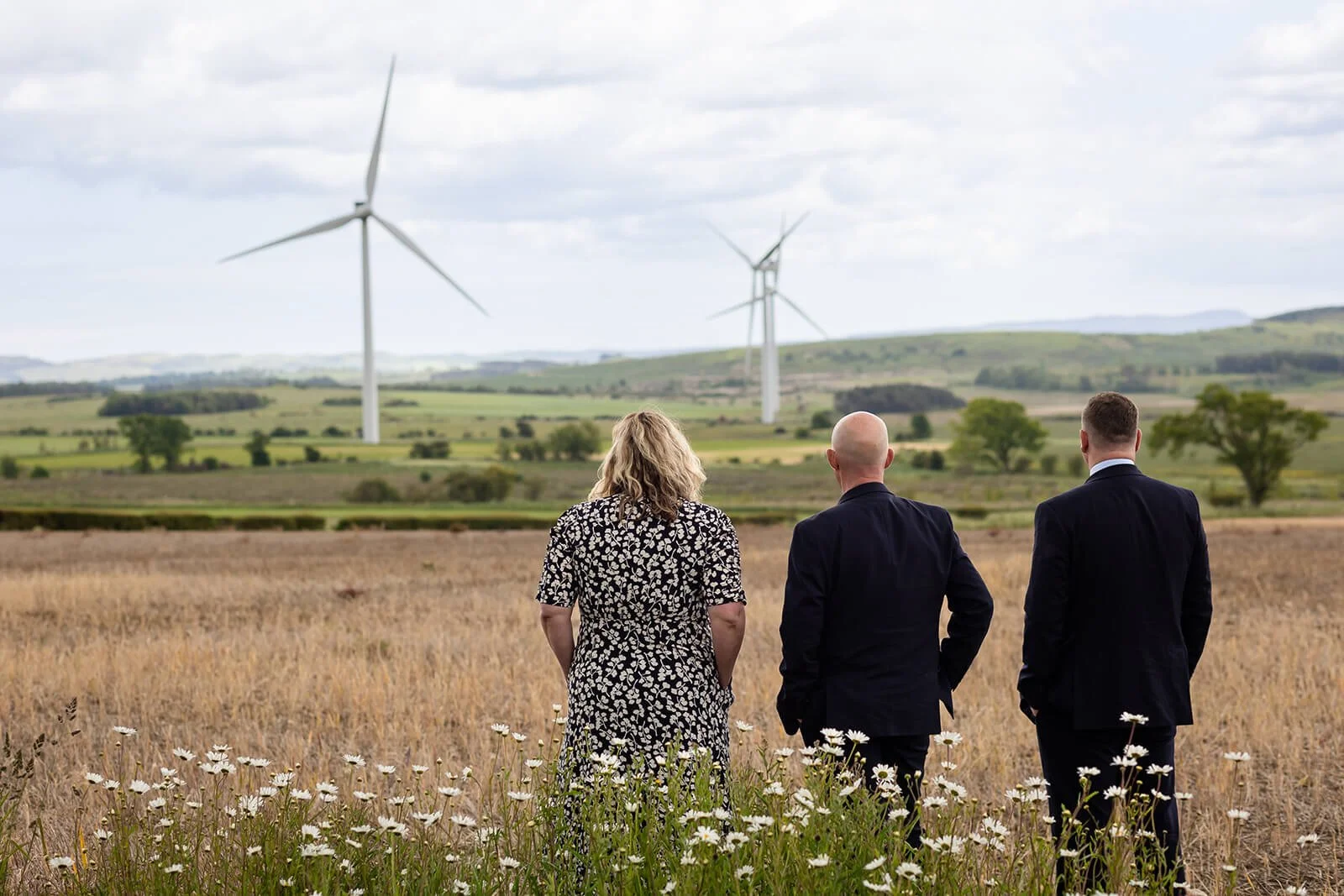three directors of greenwoods accountants  looking out to large wind farm in northumberland