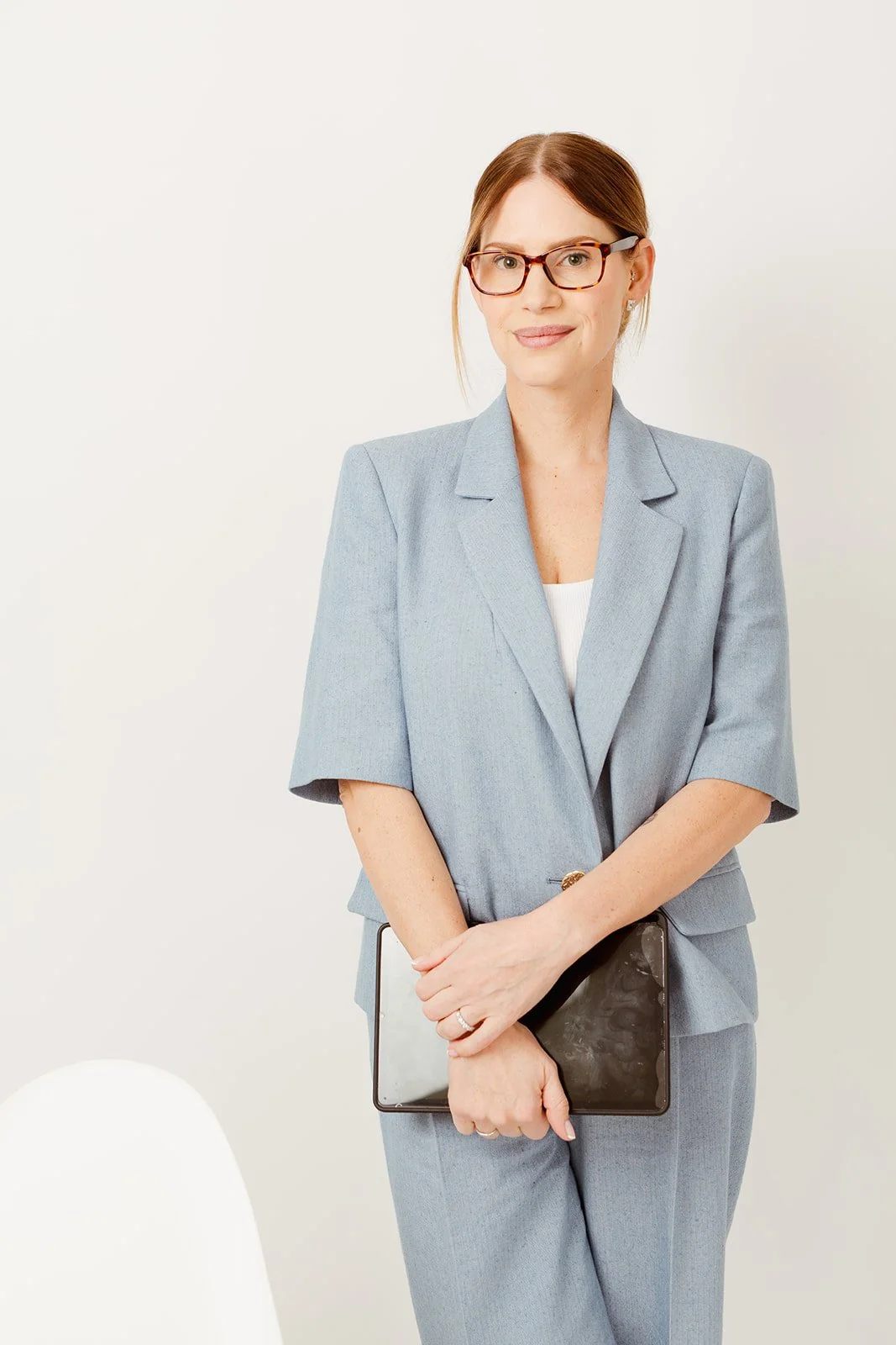 andrea stands in blue suit holding ipad for her profile picture