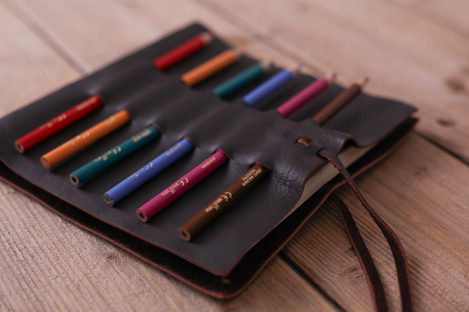 A leather handmade sketchbook with spaces on the outside for pencils to be stored