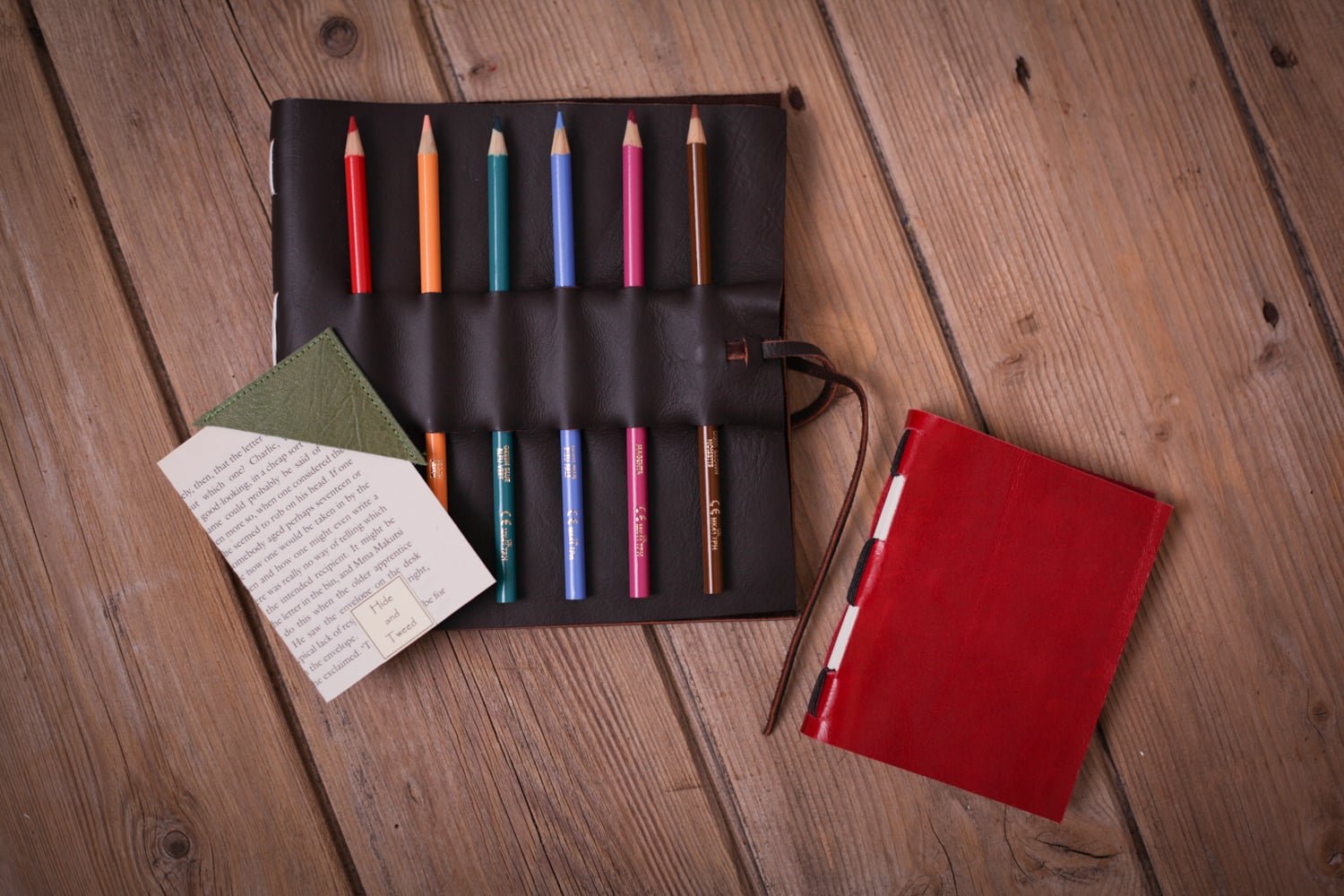 A handmade sketchbook with spaces for pencils or pens to be stored on the outside cover