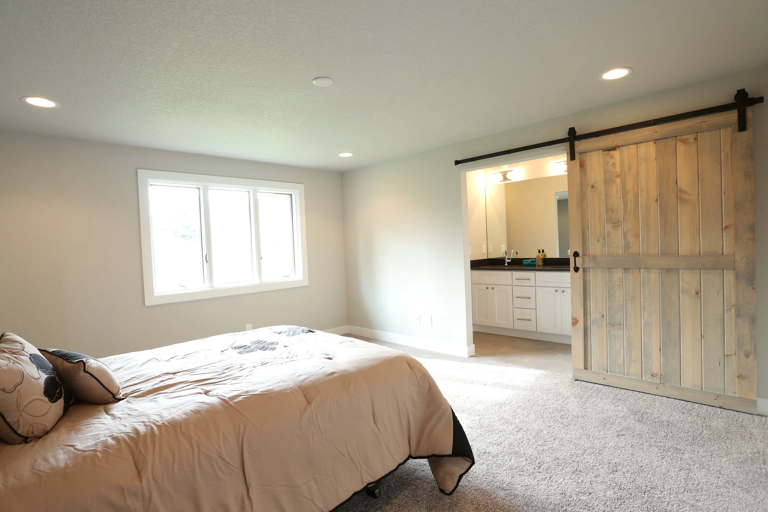 large master bedroom with custom barn door and his and her closets