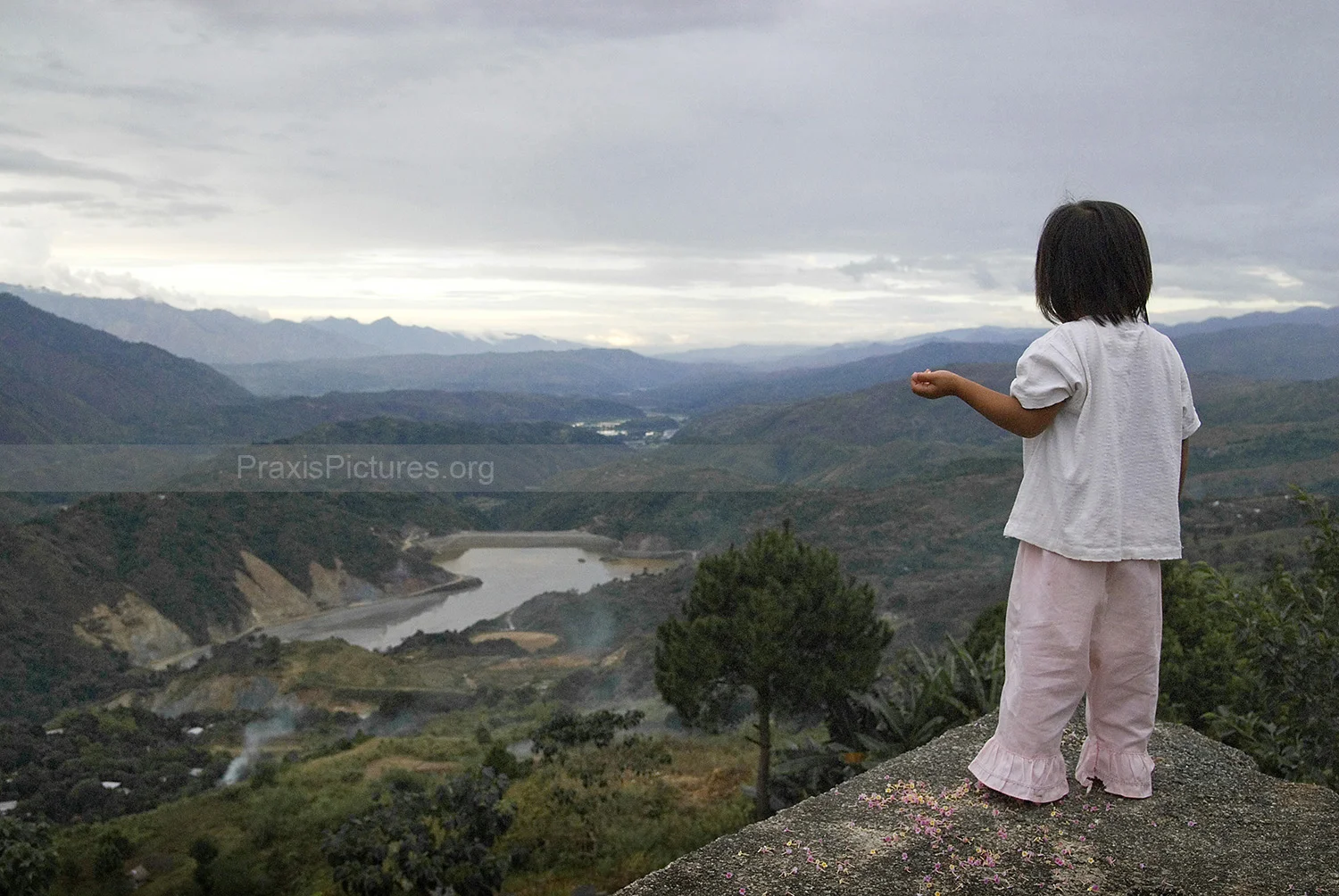 TRIXIE - Standing a few meters away from her home in Benguet province, Philippines, Trixie looks down at the tailings dam of the Victoria Gold Mine where the toxic waste from the mining process is dumped at a rate ranging between 1,500 and 2,500 metric tons per day. This is the third dam built here after the previous two collapsed. This particular dam has been completely inadequate against the torrential downpour during the yearly rainy season and is especially vulnerable to earthquakes as Benguet is directly above a fault line. For years the chemicals have been leaking out into the nearby river systems.