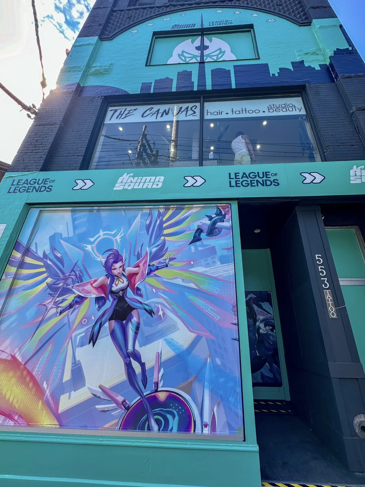 Colorful pop-up space facade featuring a digital illustration of Seraphine from League of Legends, set against a vibrant backdrop of light blue, green, yellow, and purple. Her signature purple hair and wings create a striking focal point.
