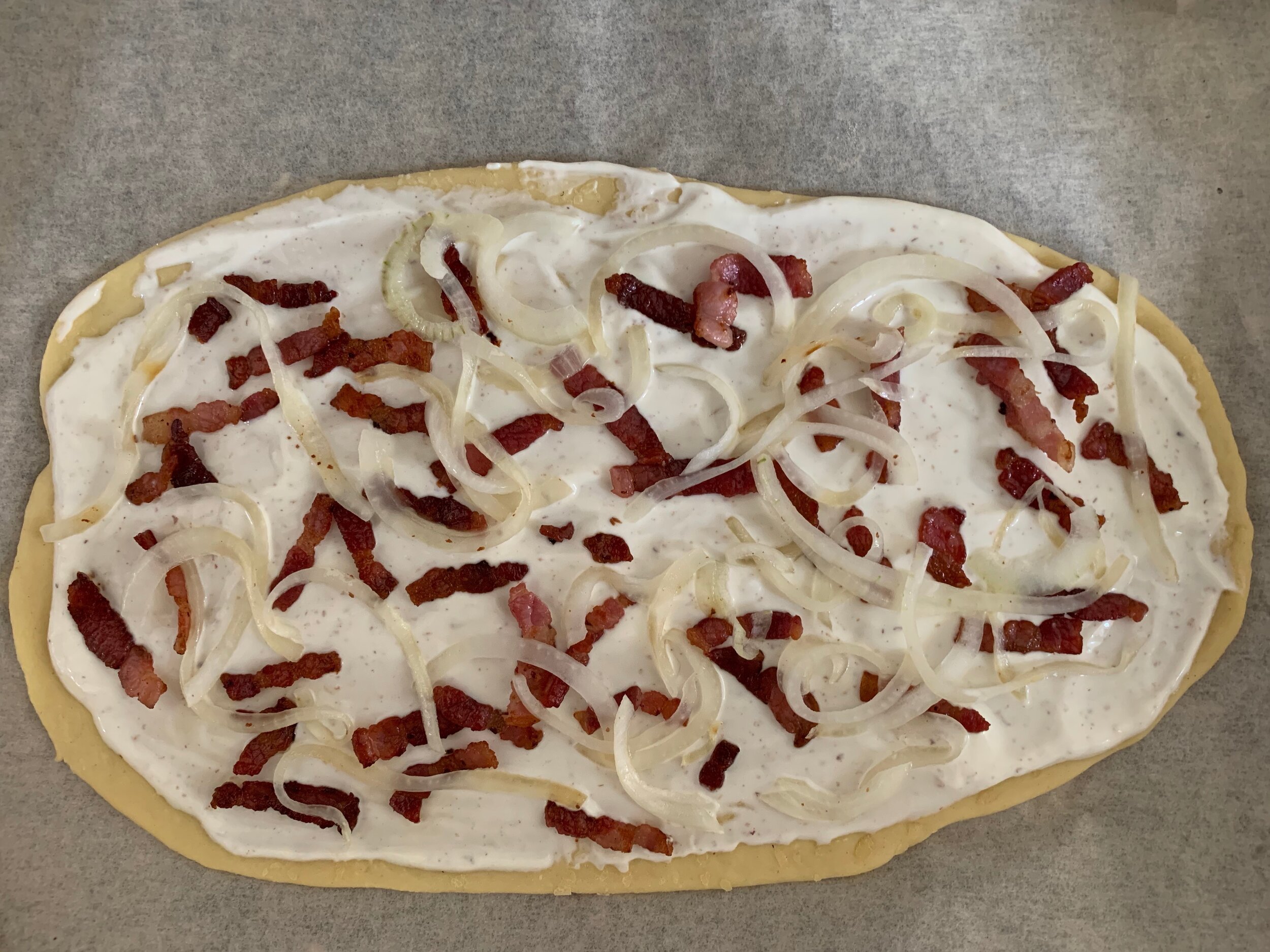 Assembled tarte flambée ready to go in the oven
