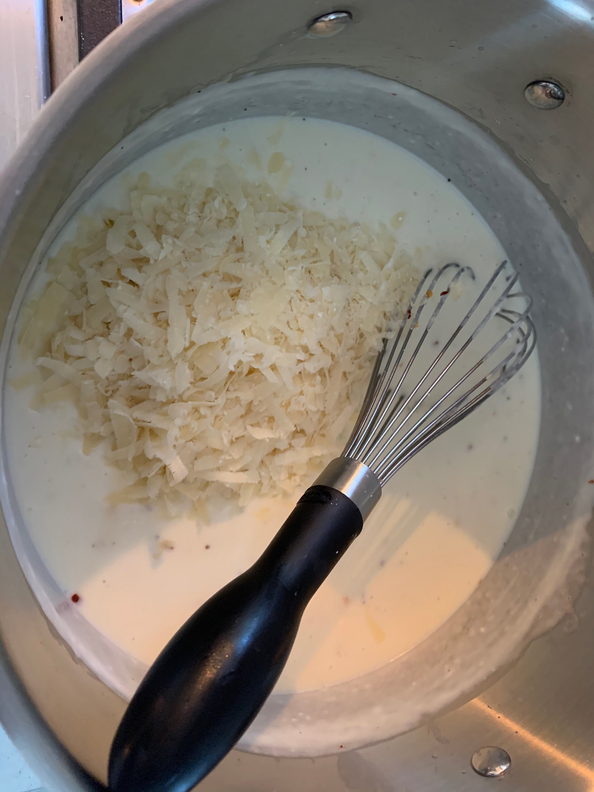 Cheese being added after the sauce has been removed from the heat
