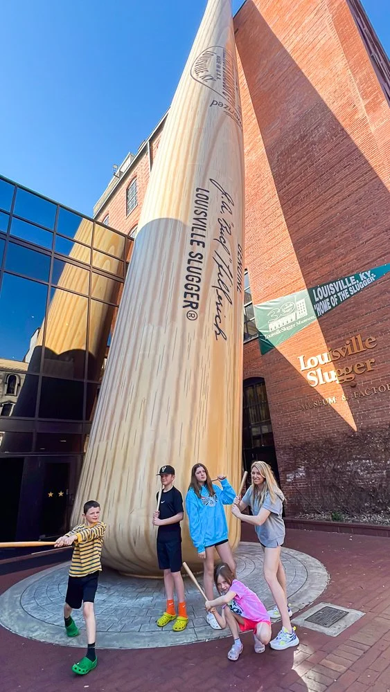 posing in front of giant bat at Louisville Slugger Museum