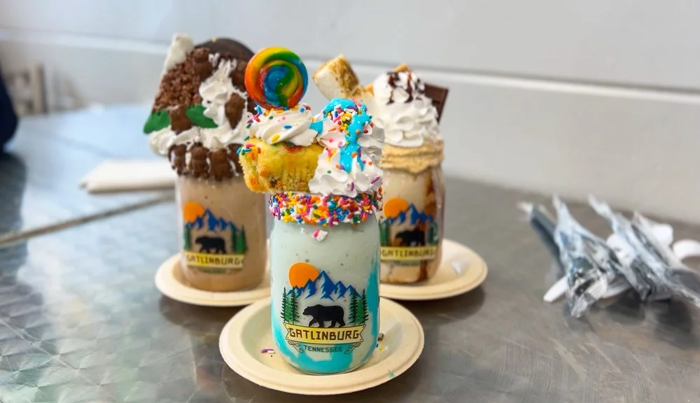 3 milkshakes in mason jars with desserts on top