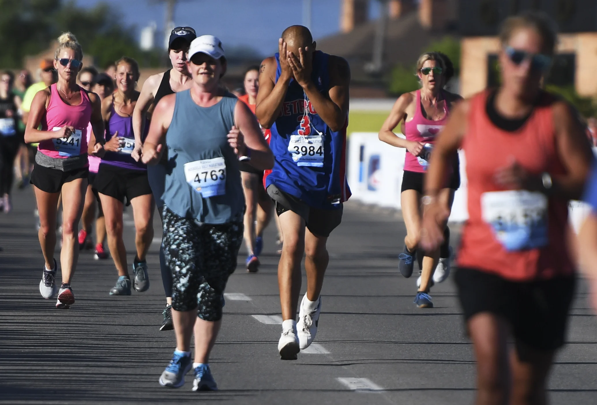 Davie Mizerek (3984), from Odesa, Wash., wipes the sweat from his face as he approaches the finish line for the half marathon on the Higgins Street bridge.