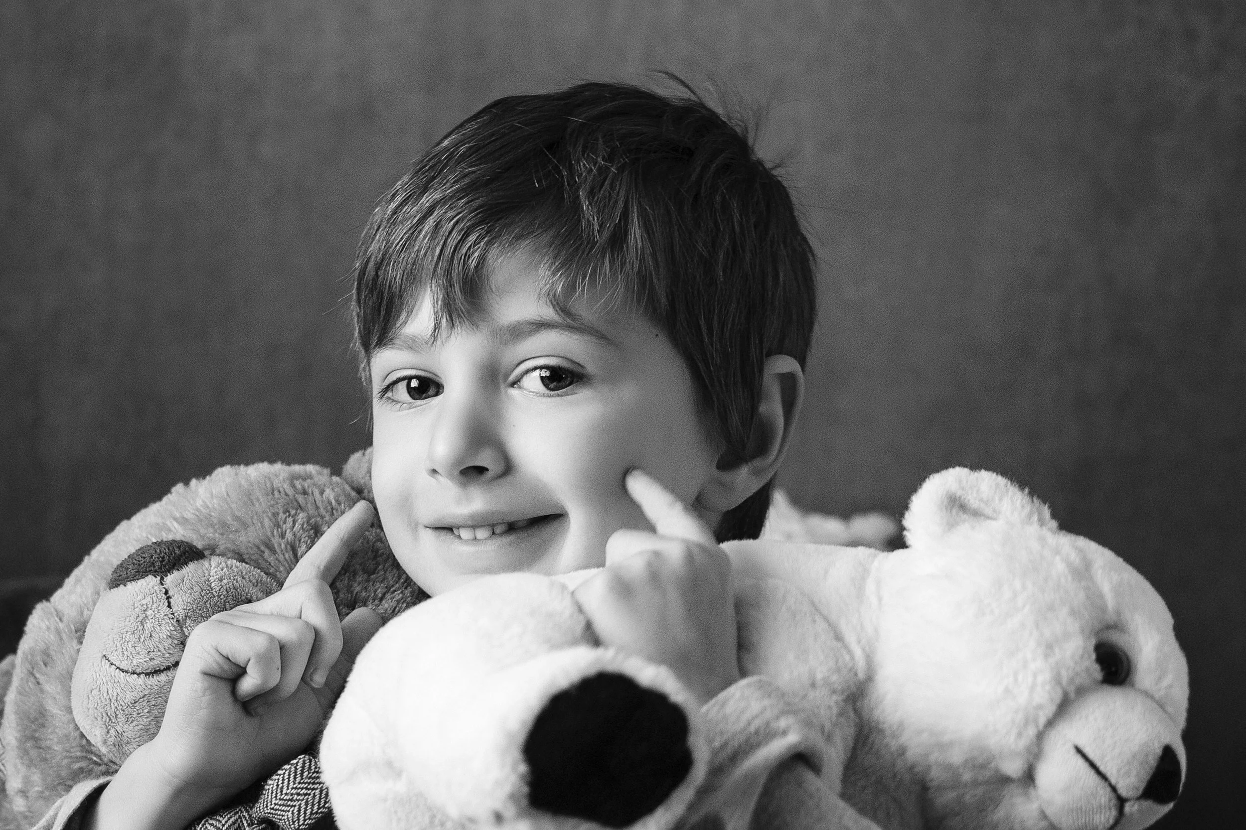 A young boy with short dark hair and bright eyes, smiling during mommy and me mini session in Troy, Michigan, in black and white.
