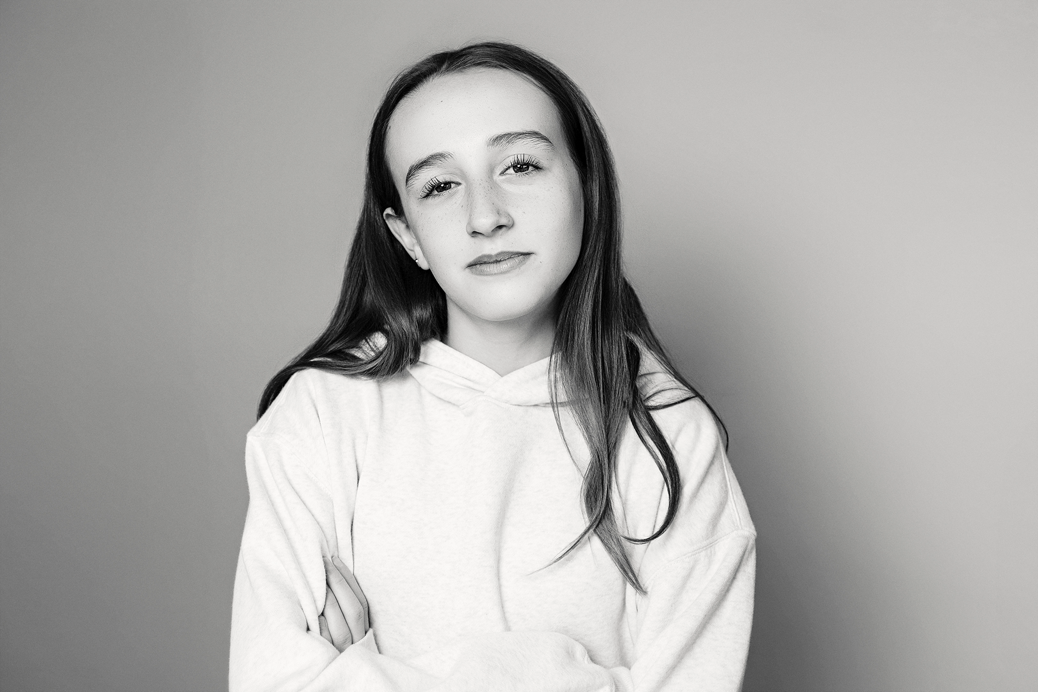 Black-and-white portrait of a young girl with long hair, looking at the camera with a neutral expression, wearing a light-colored hoodie during mommy and me mini session in Northville, Michigan.