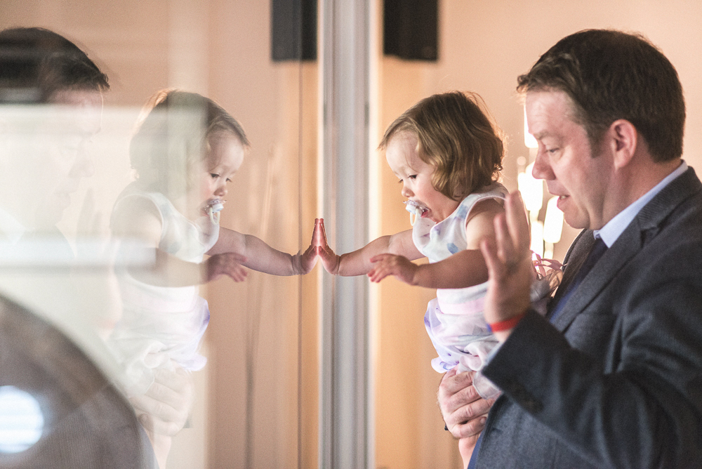 Dad and Daughter look out of a glass window catching thier reflections in the glass