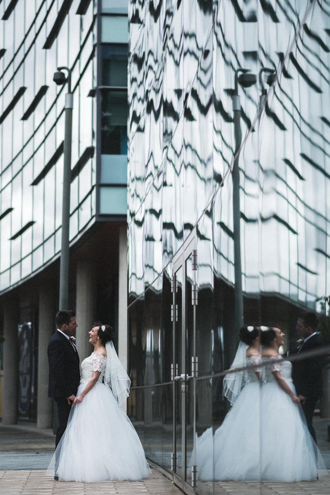 Bride and groom pose for photos with a reflection in Media City Salford Wedding