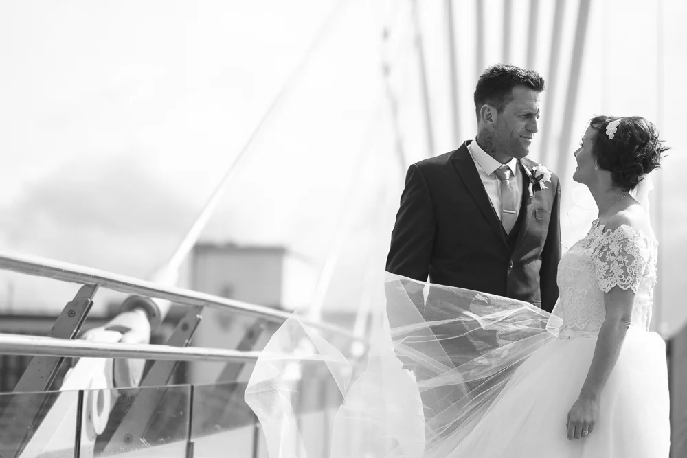 Bride and groom look lovingly at each other on Salford's Media City bridge