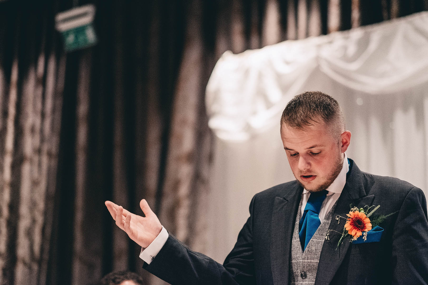 Groom holds his hand in the air during speech