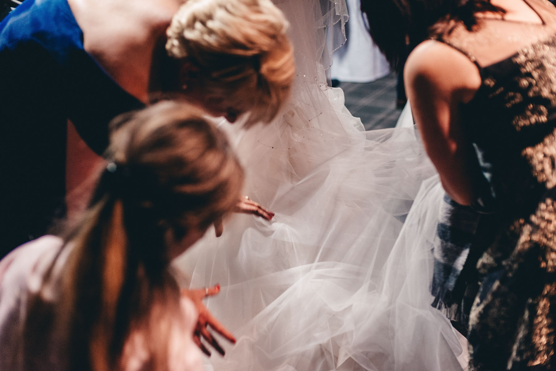 Guests help bride with her dress