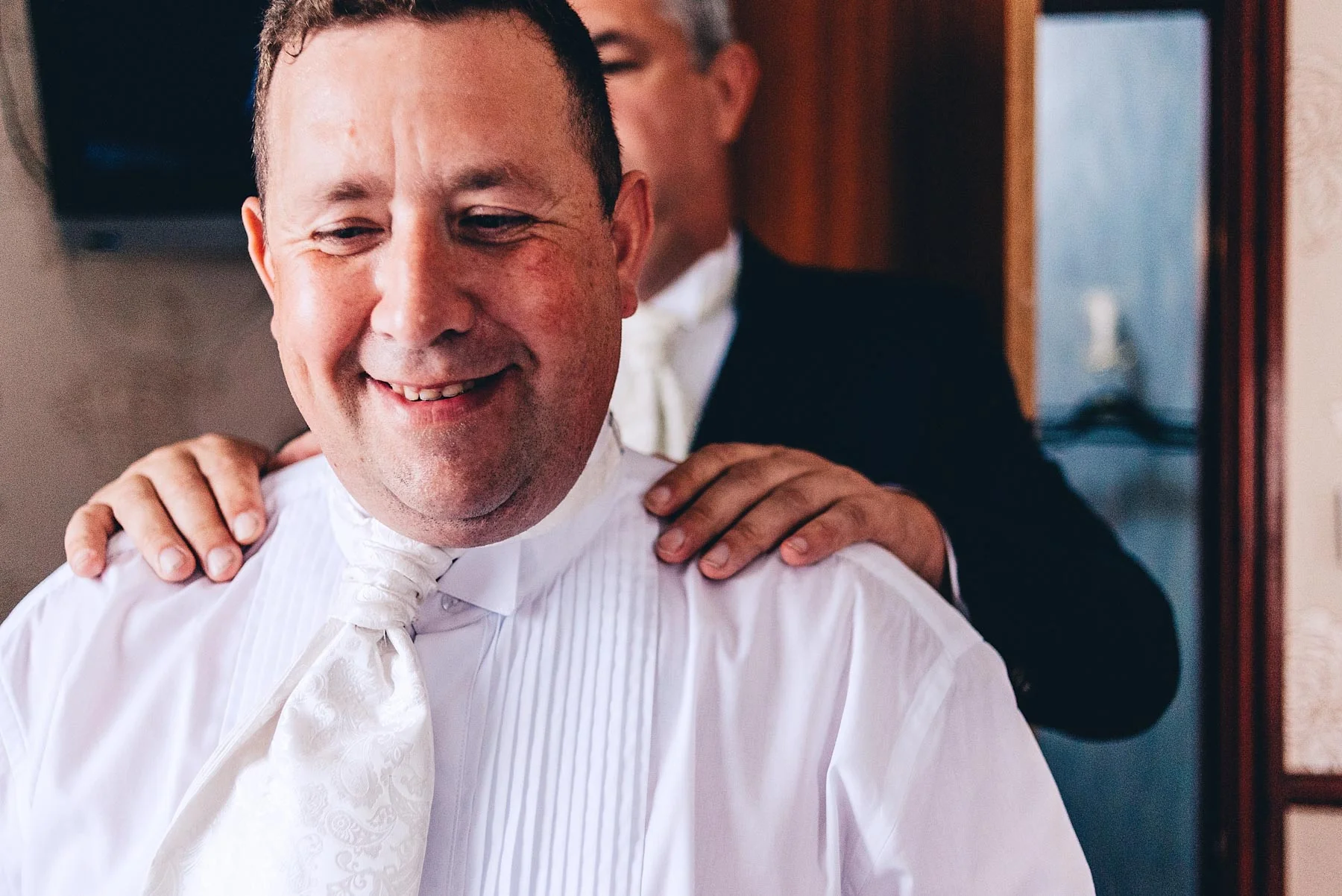 Groom looks happy with best mans hand on his sholder