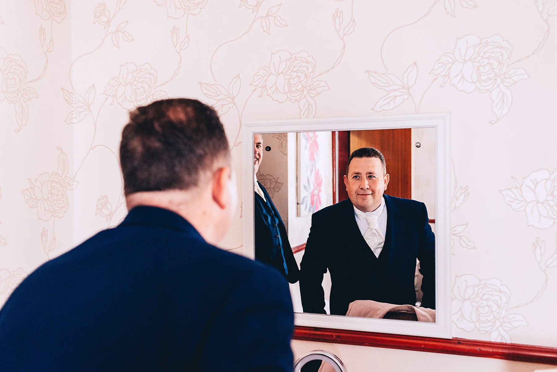 Groom looks in the mirror