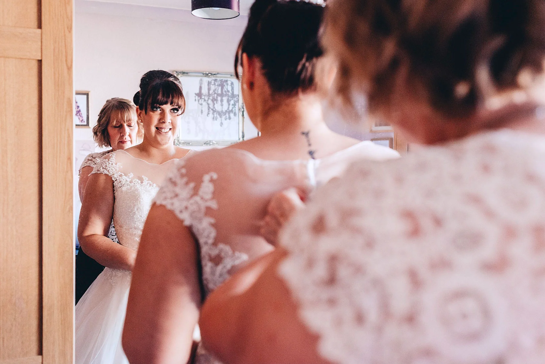 Bride looks in mirror as her mother helps her get ready