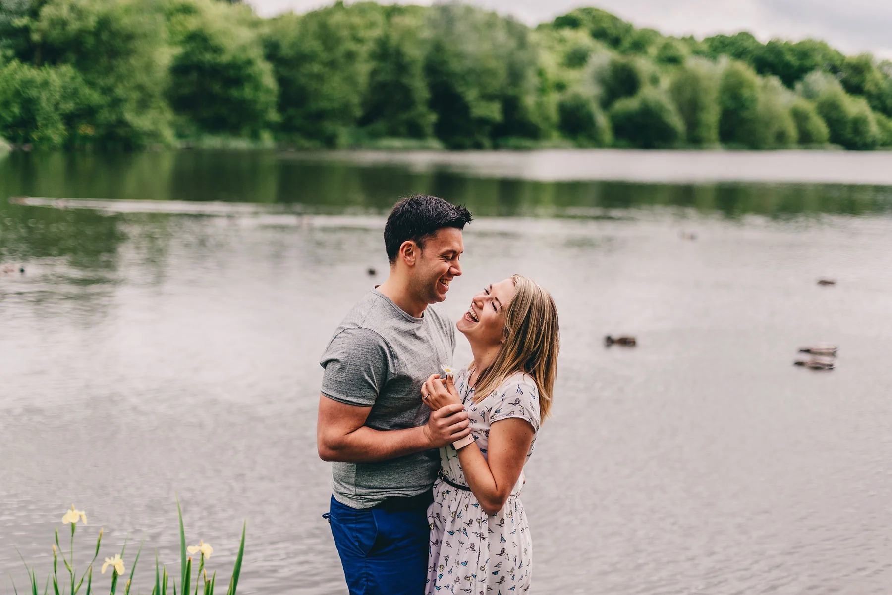 Engaged couple pose in front of lake during engagement shoot
