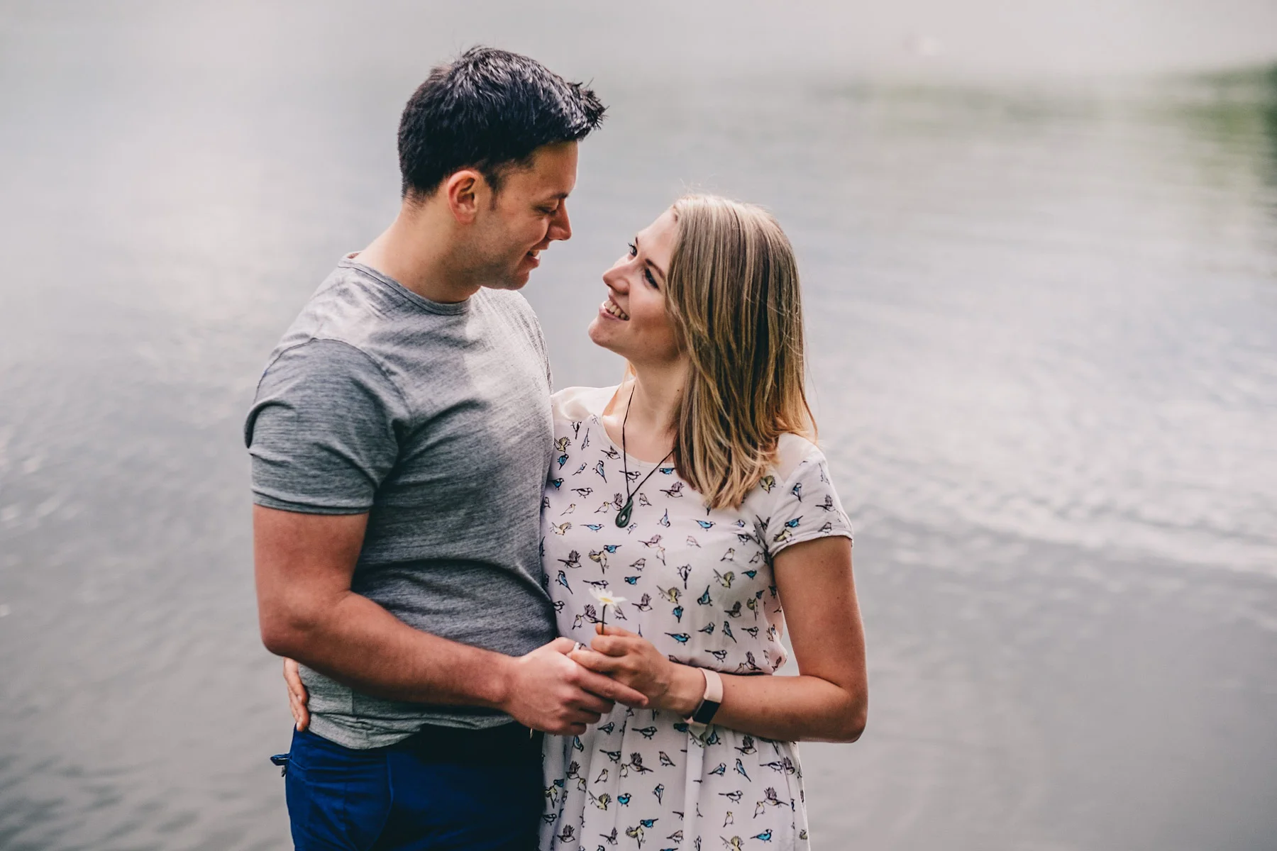 Engaged couple pose in front of lake during engagement shoot in Holmebrook Valley Country Park
