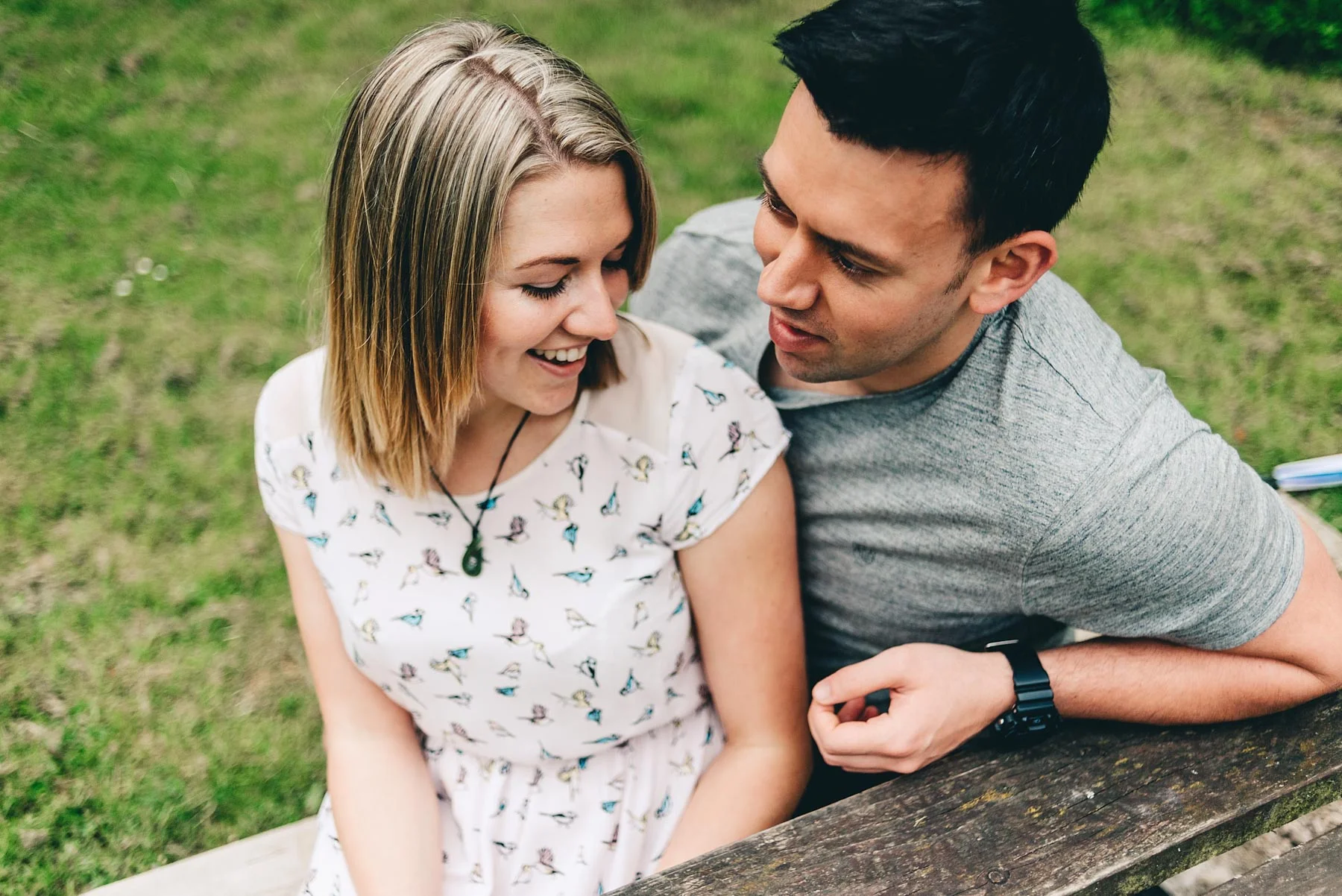 Engaged couple pose sitting down during engagement shoot
