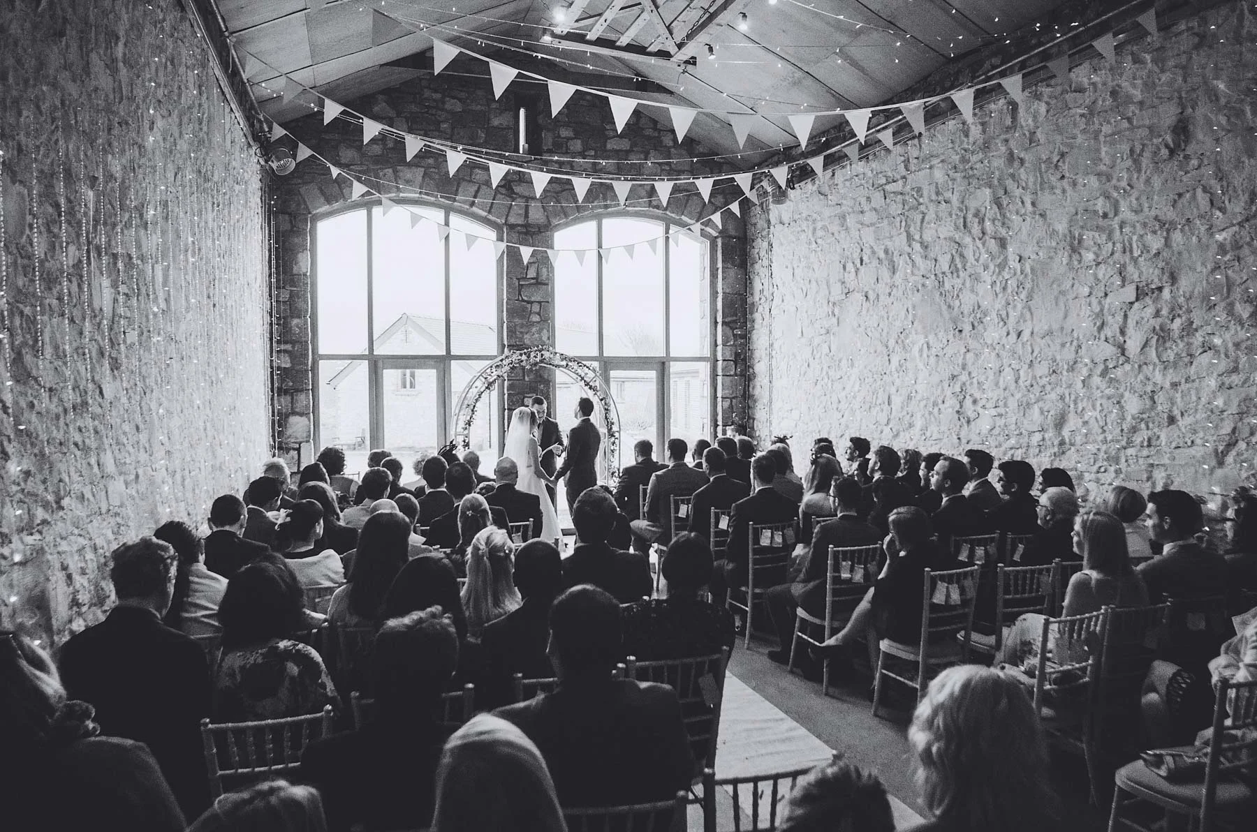 Bride and groom are watched by guests during wedding at Rosedew Farm Llantwit Major South Wales