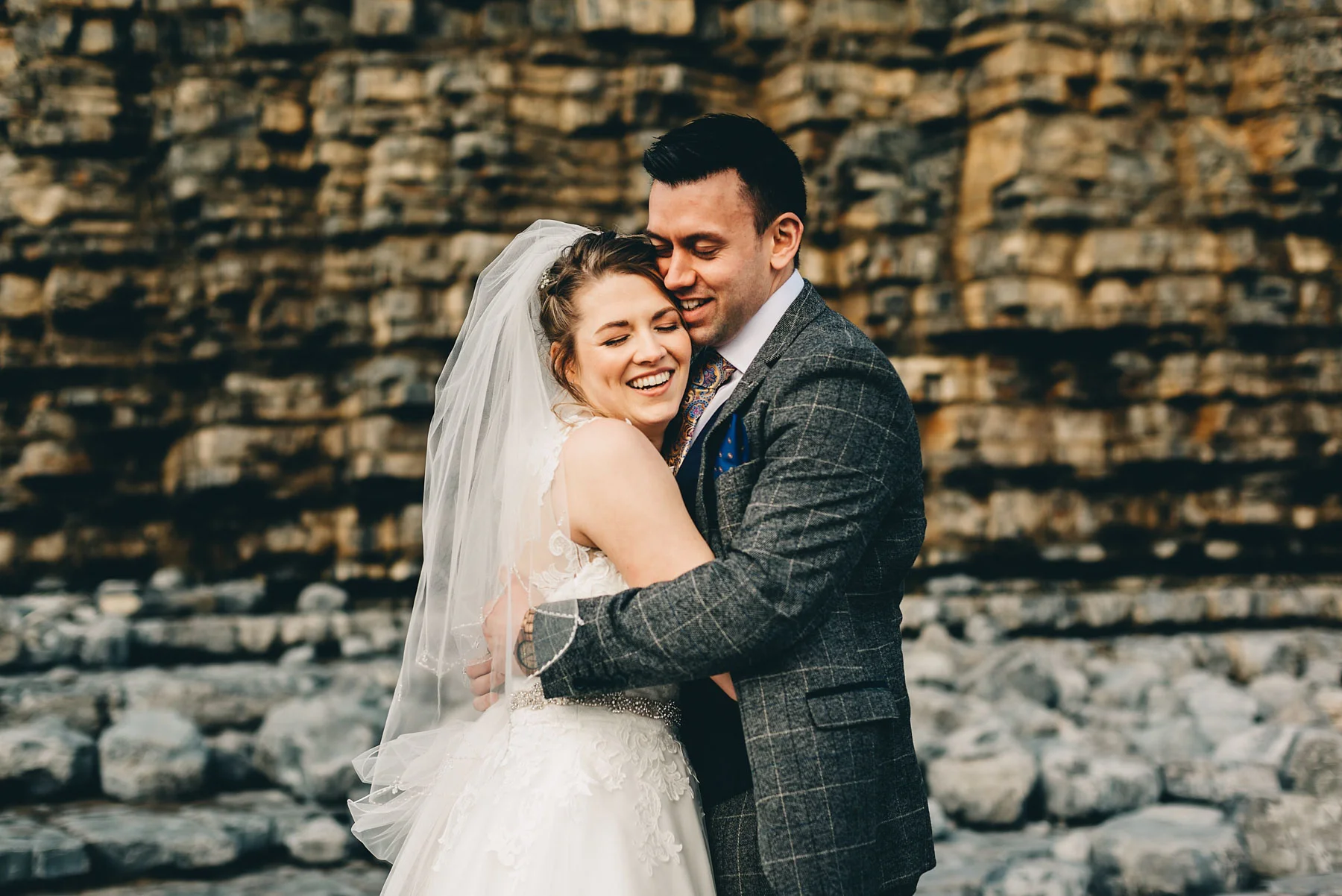 Couple just married hug by cliffs at Llantwit Major, South Wales
