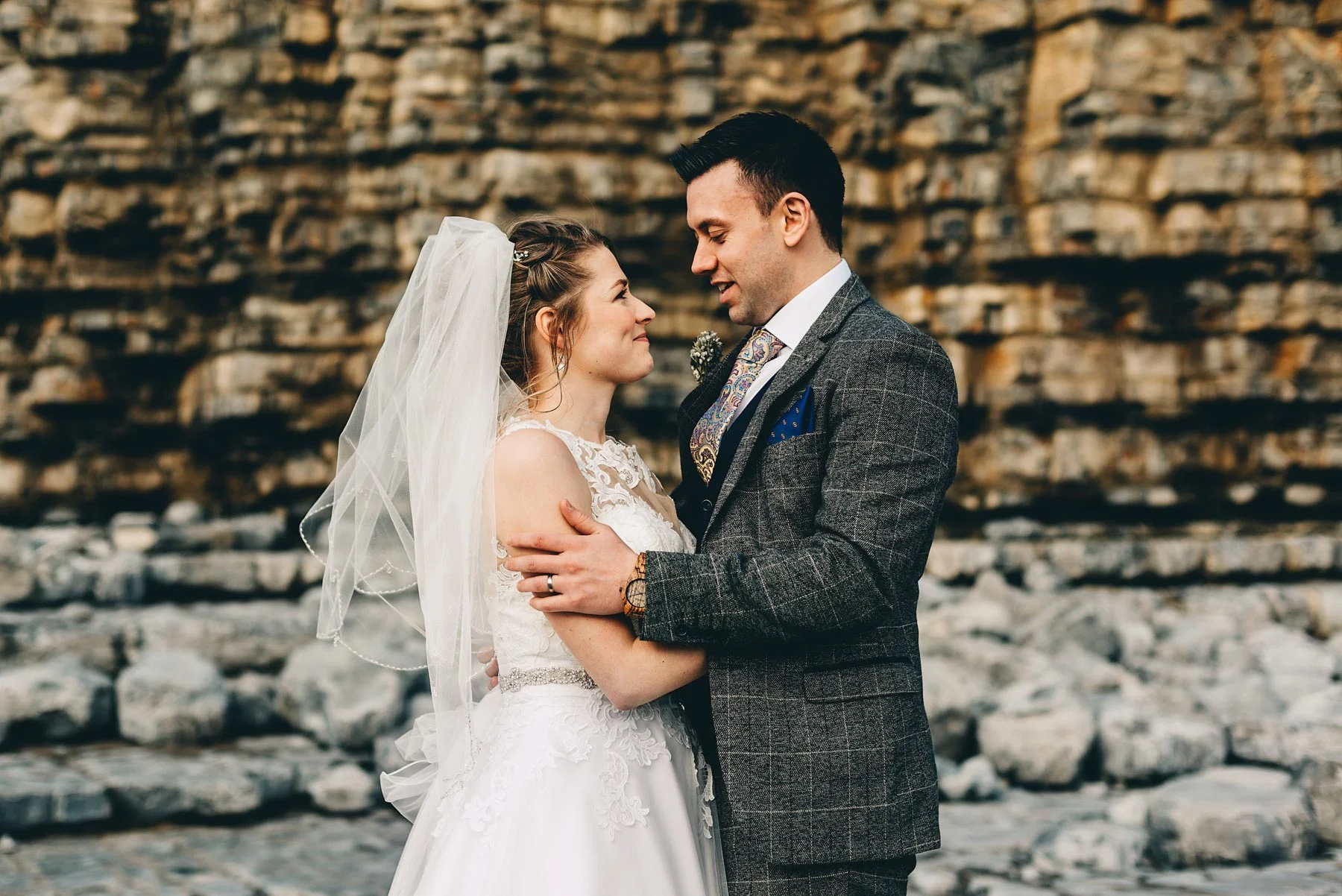 Couple just married stare lovingly by cliffs at Llantwit Major, South Wales