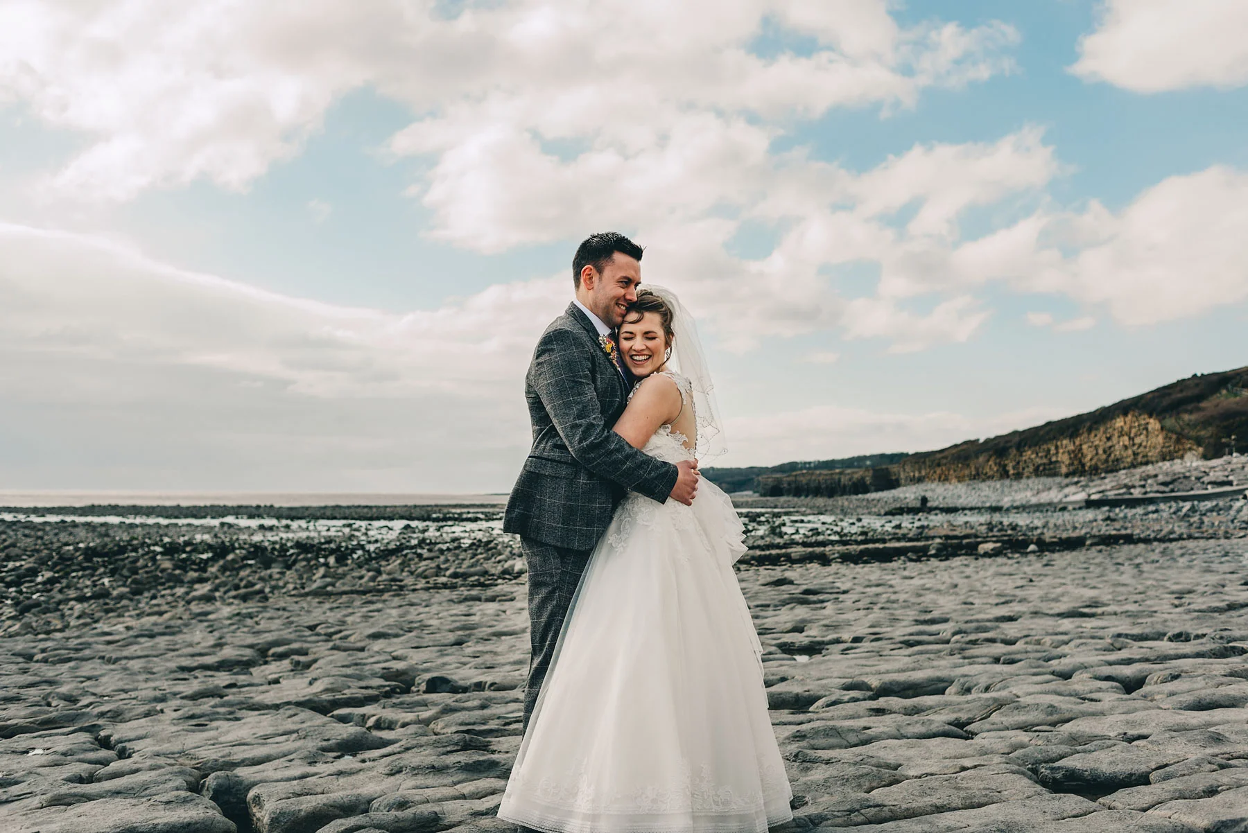 Couple just married hug by coast at Llantwit Major, South Wales