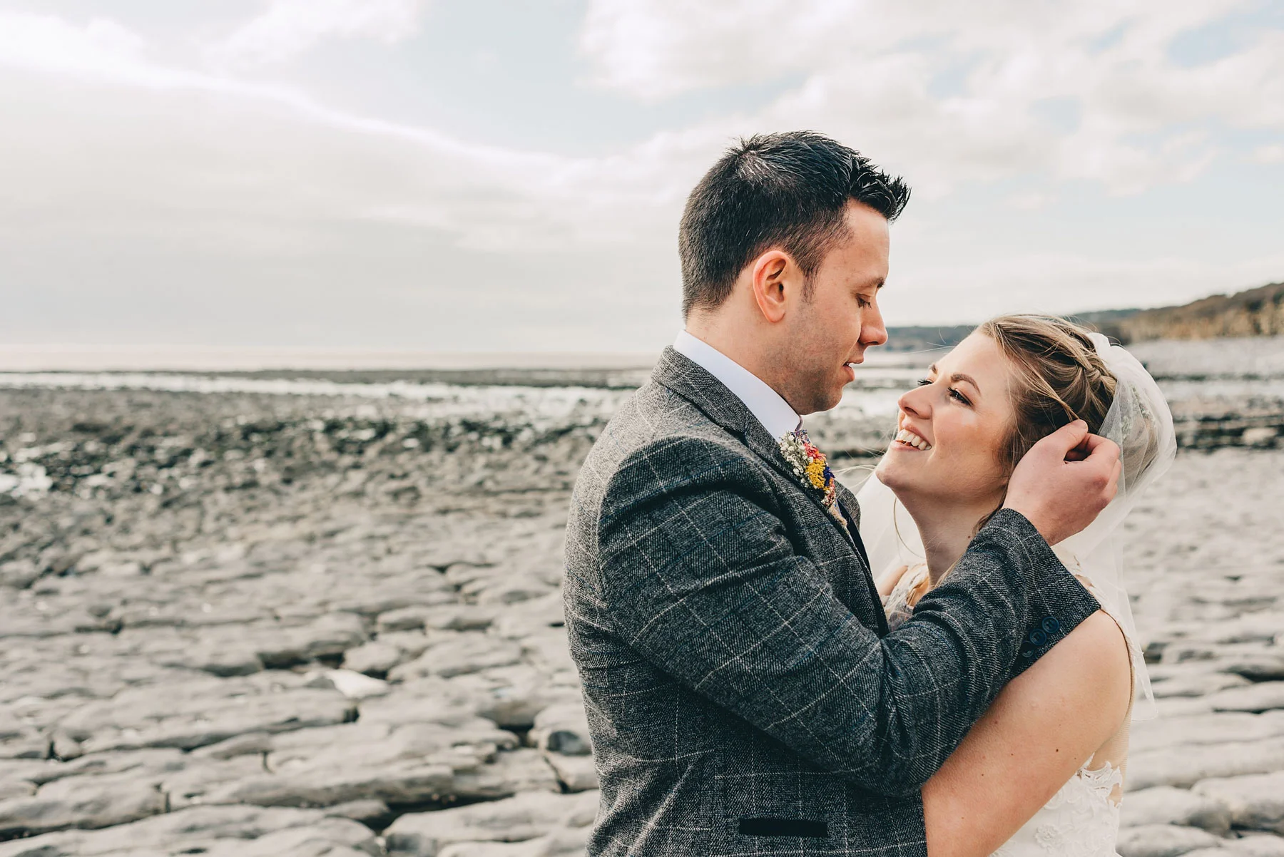 Couple just married stare lovingly at each other by the coast at Llantwit Major, South Wales