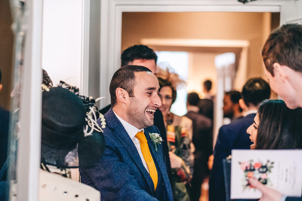 Groom laughs with friends during wedding evening