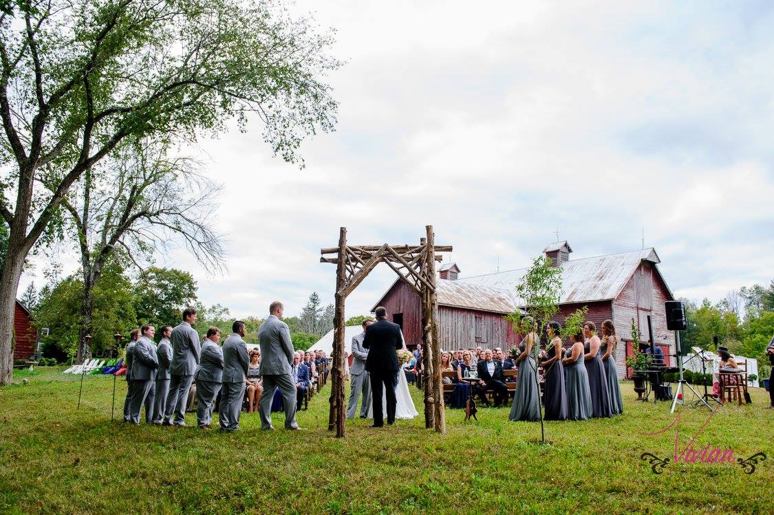 bridal-couple-standing-under-arbor-with-barn-in-background.jpg