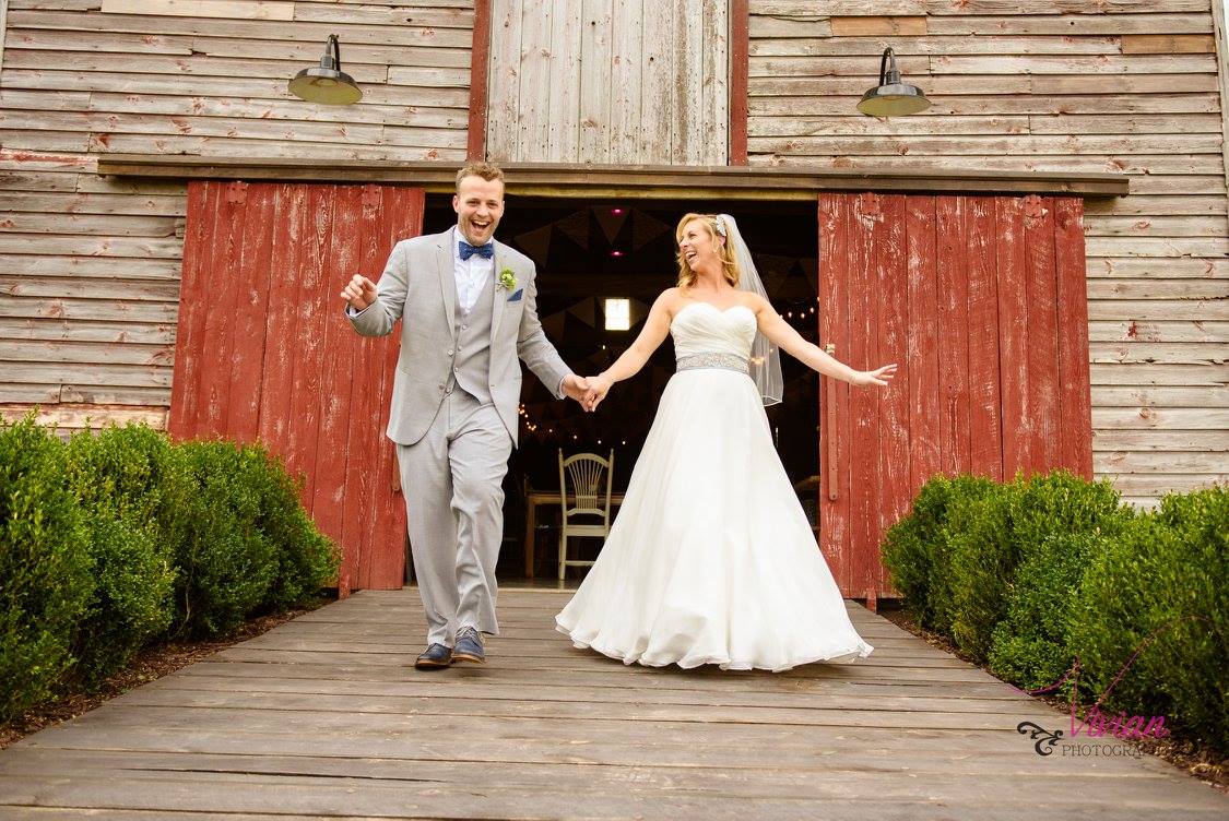 bride-and-groom-posing-outside-rustic-barn-wedding-venue.jpg