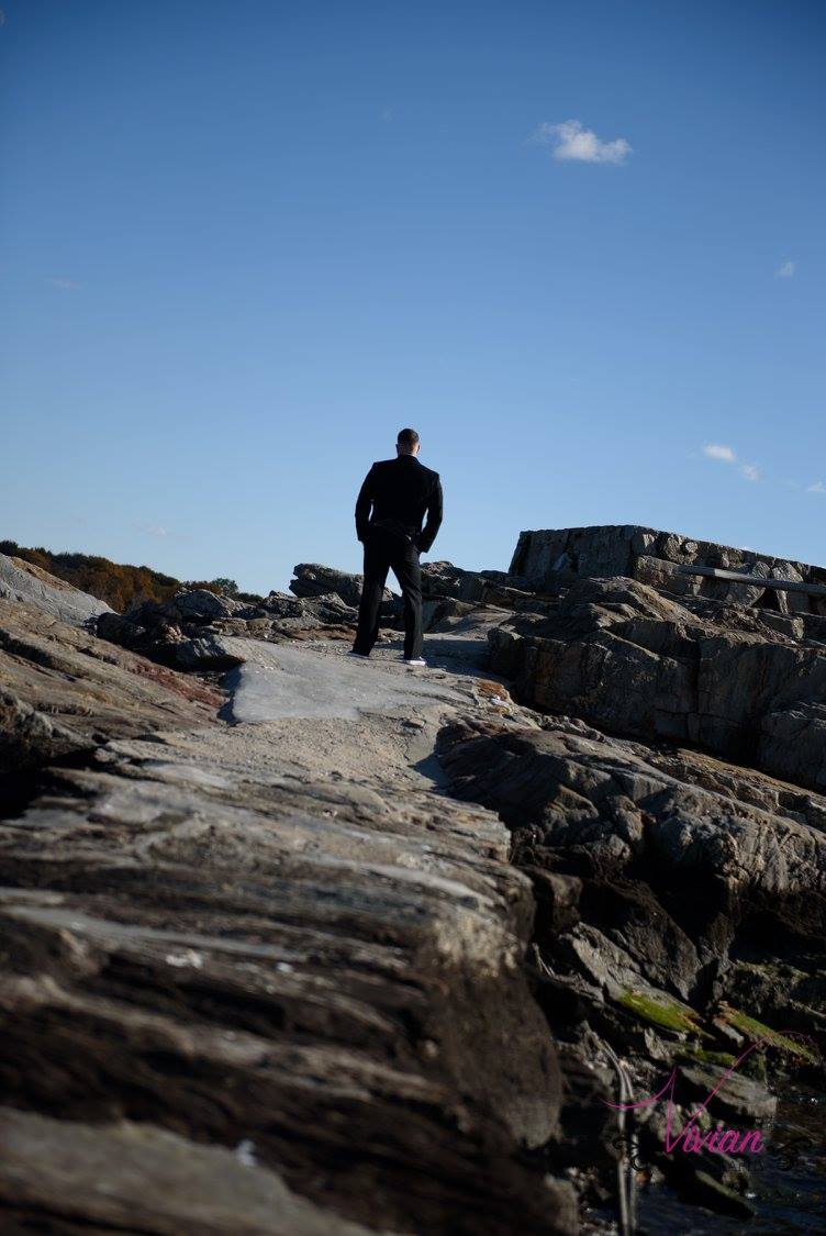 groom-standing-on-rocks-far-away-with-blue-sky.jpg