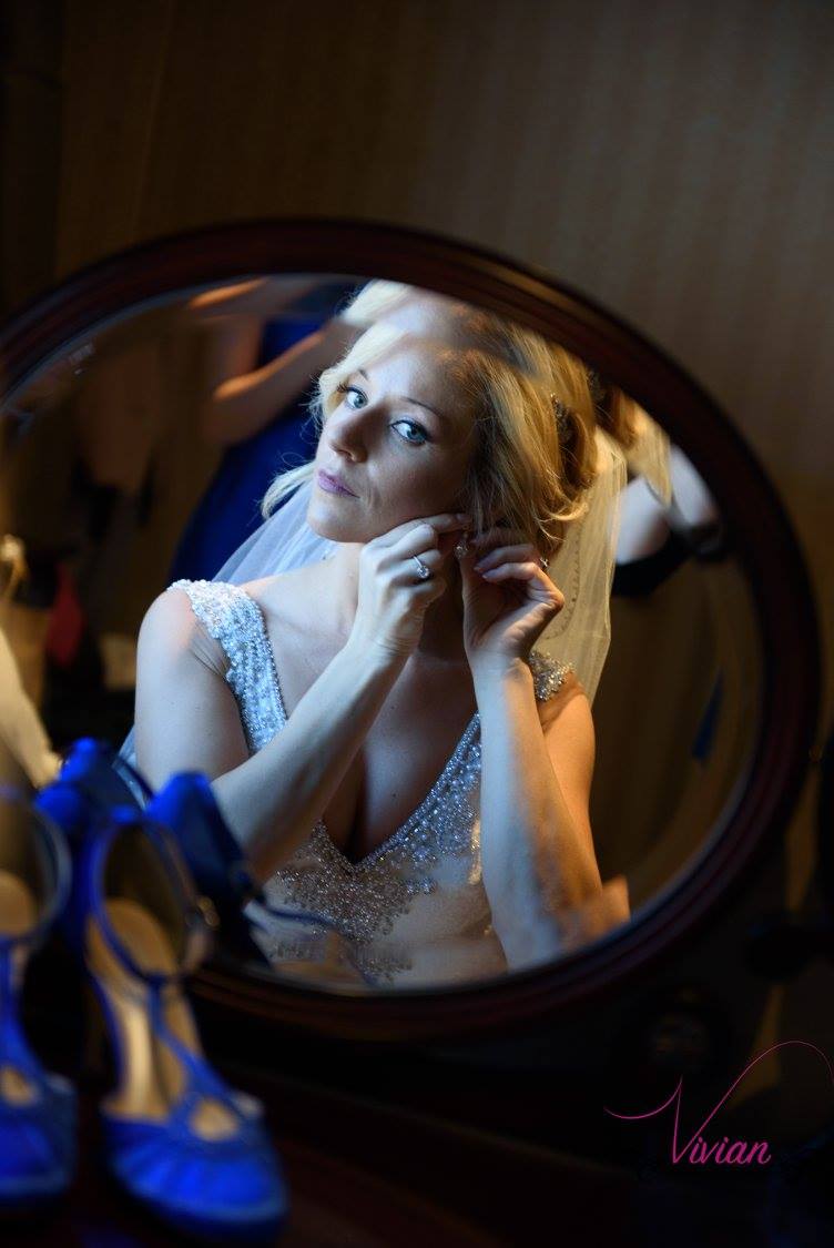 reflection-of-bride-putting-on-earrings-at-vanity.jpg